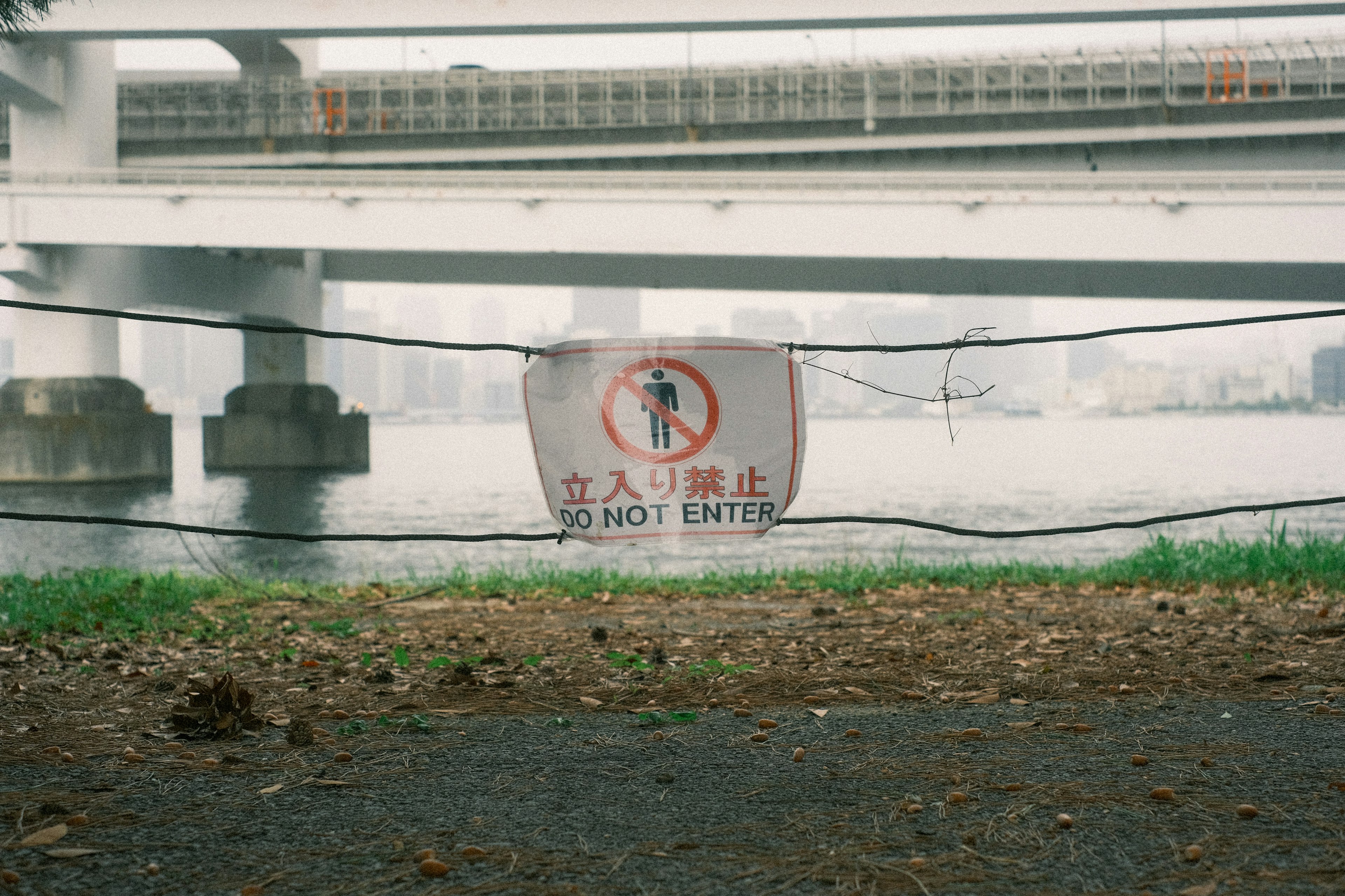 Papan larangan masuk di bawah jembatan dengan pemandangan sungai