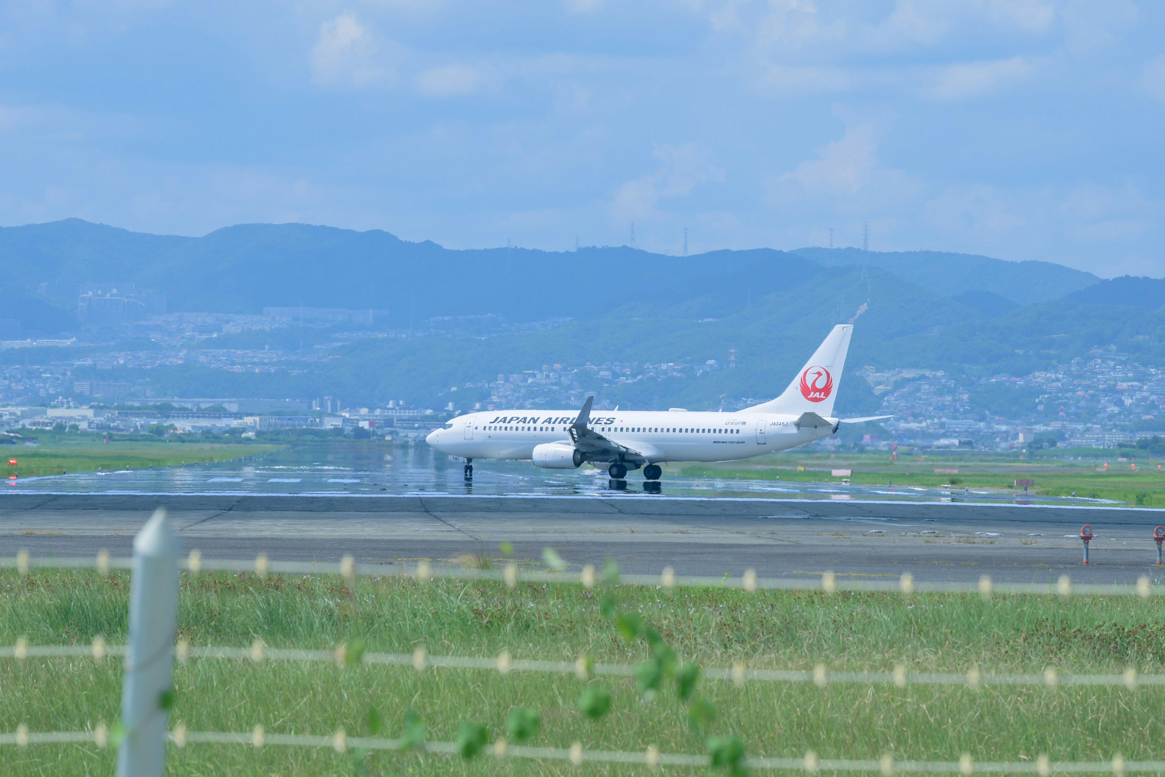 Aircraft landing on runway with blue sky and mountains in background