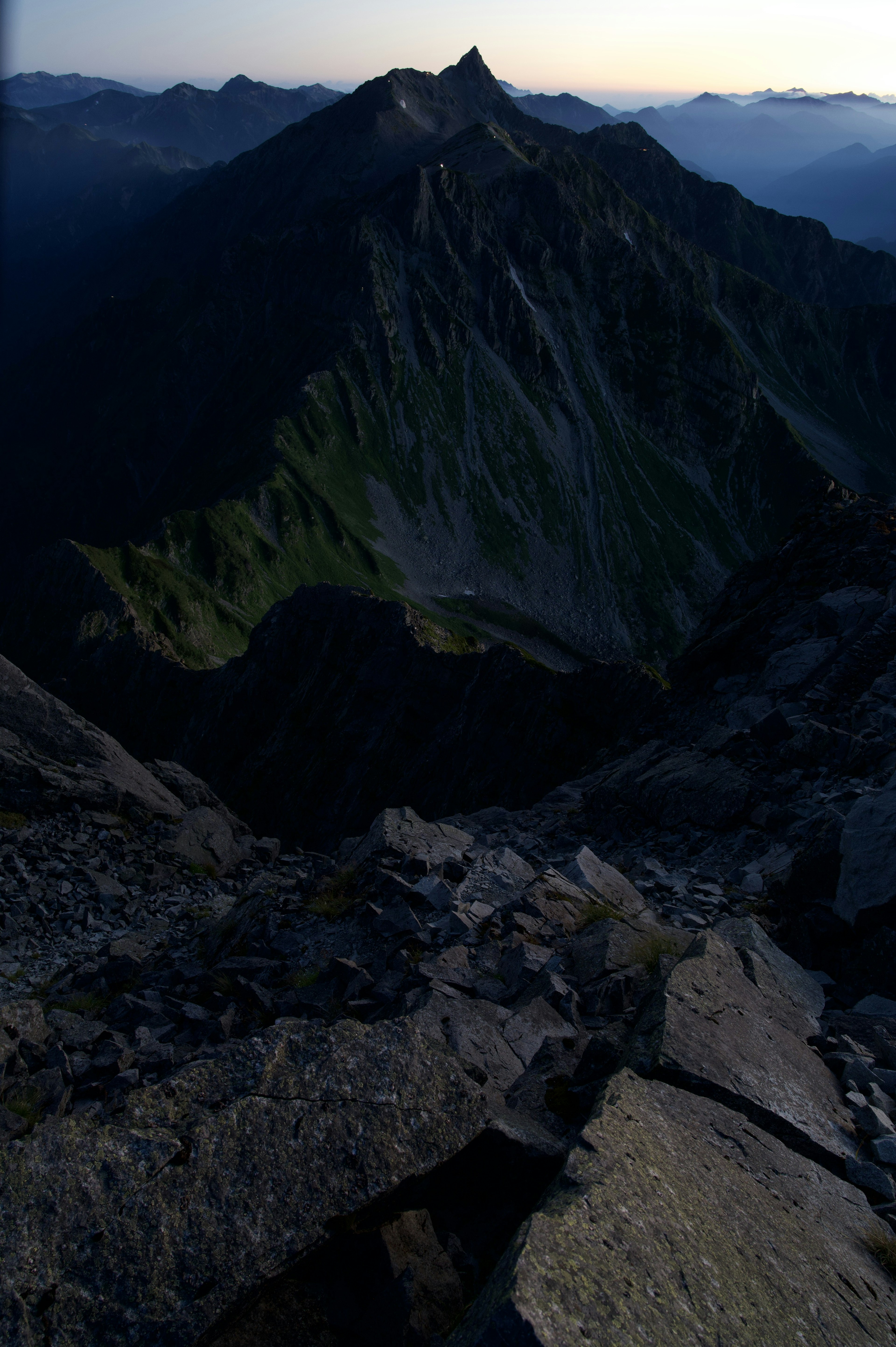 View from mountain summit featuring rugged rocks and green slopes