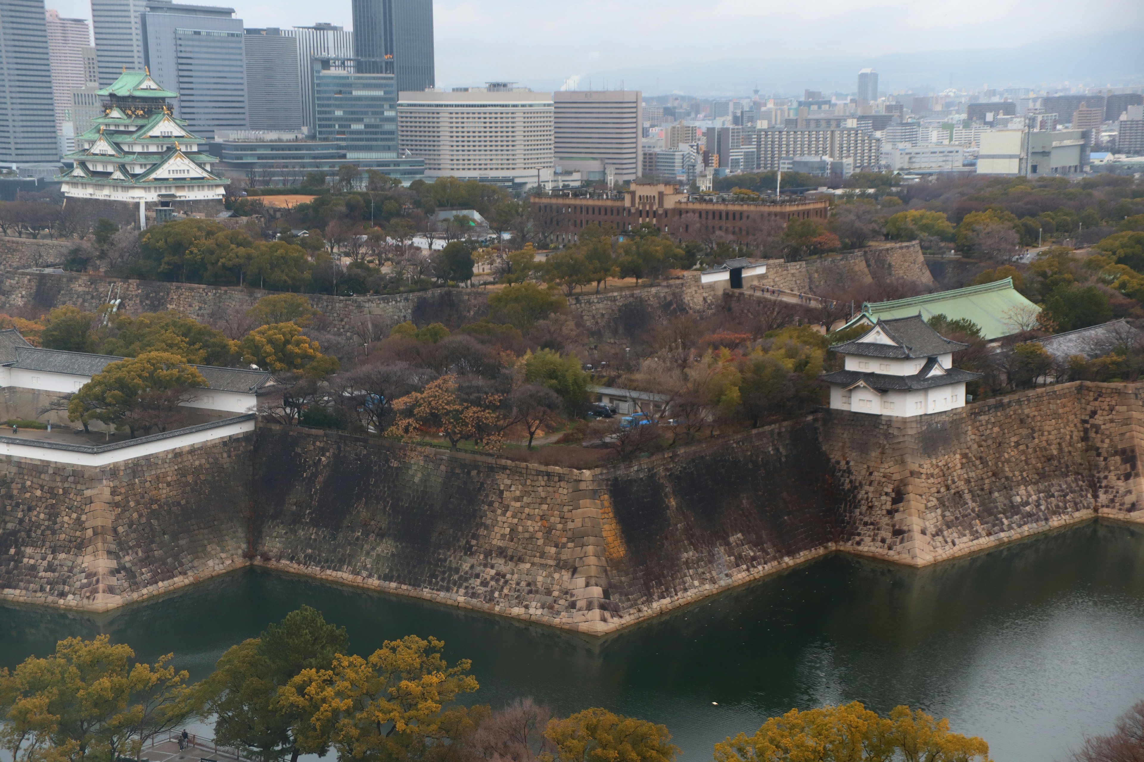 Cảnh lâu đài Osaka với những bức tường đá cổ và cây xanh xung quanh