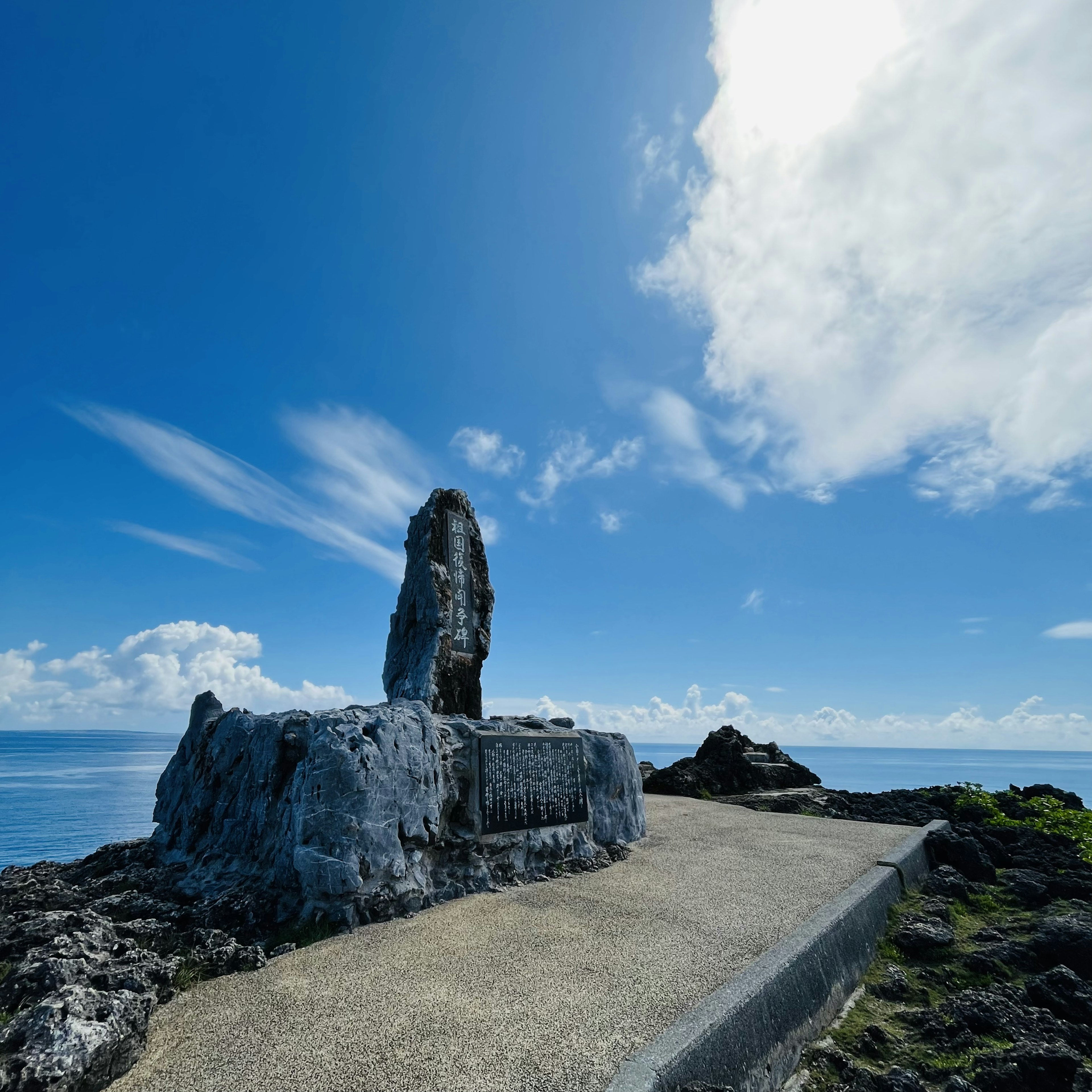 Monument en pierre sous un ciel bleu avec un chemin pavé