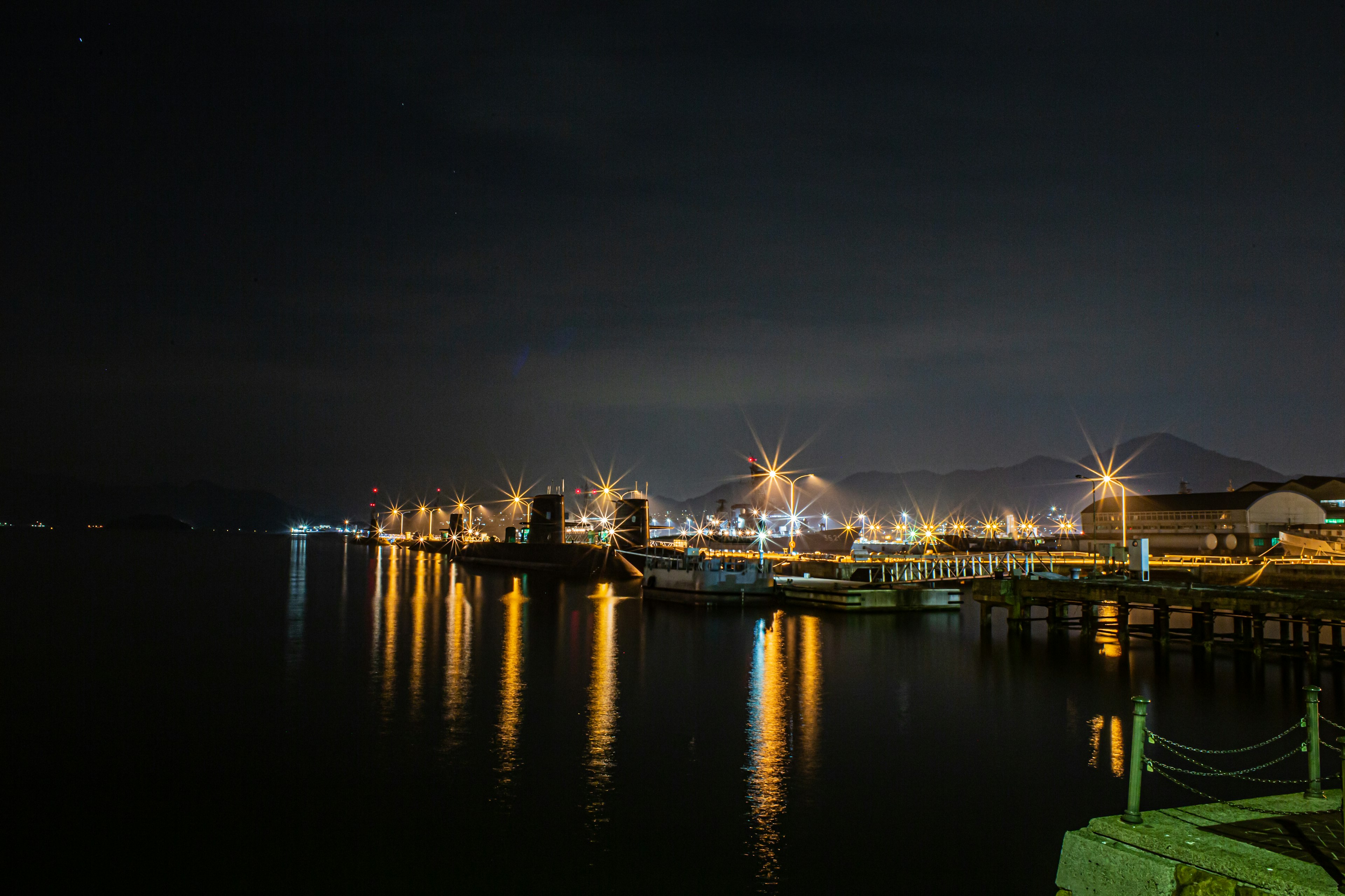 Escena nocturna de un puerto luces reflejándose en el agua