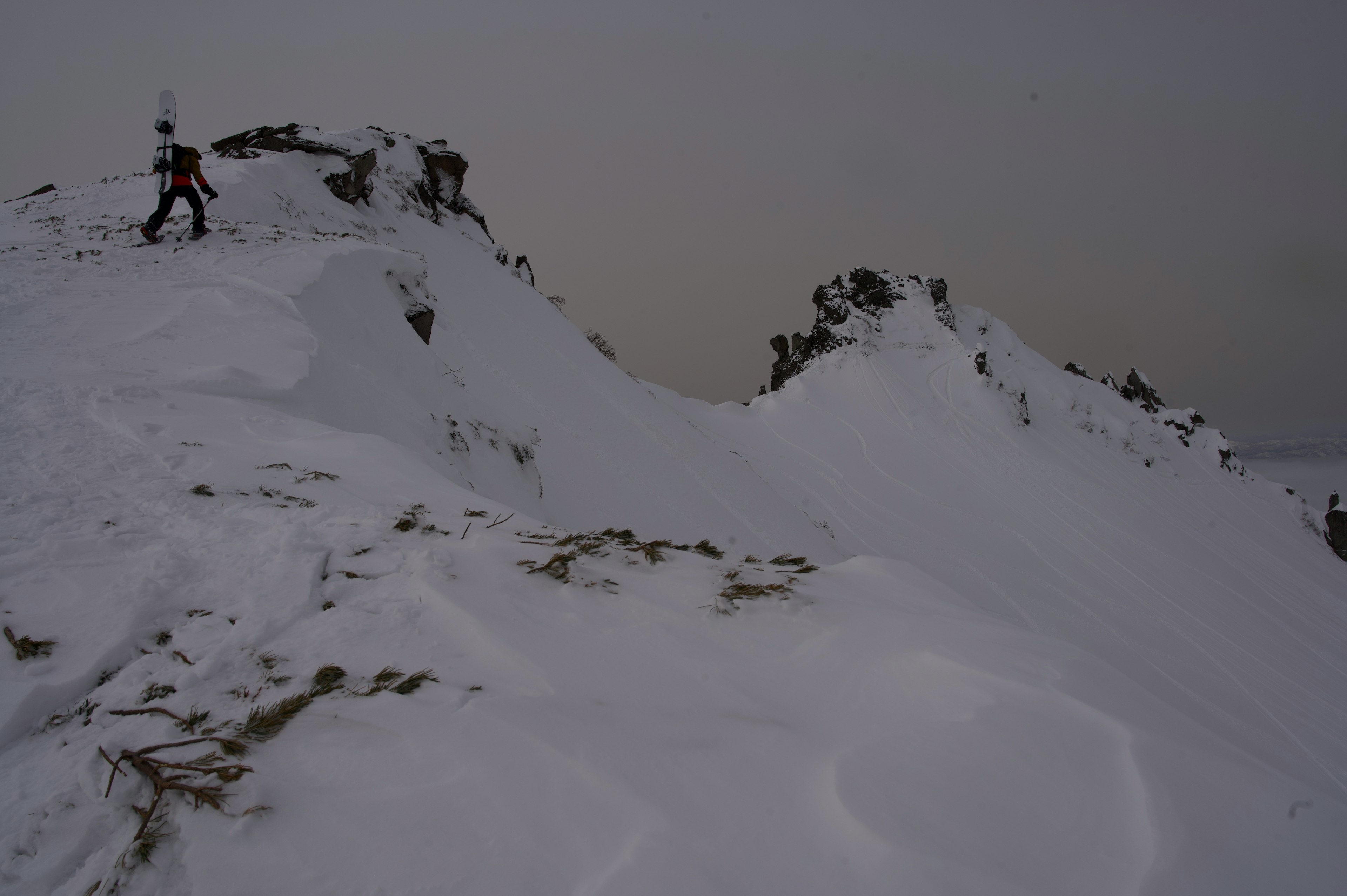 Un excursionista atravesando un paisaje montañoso nevado bajo cielos nublados