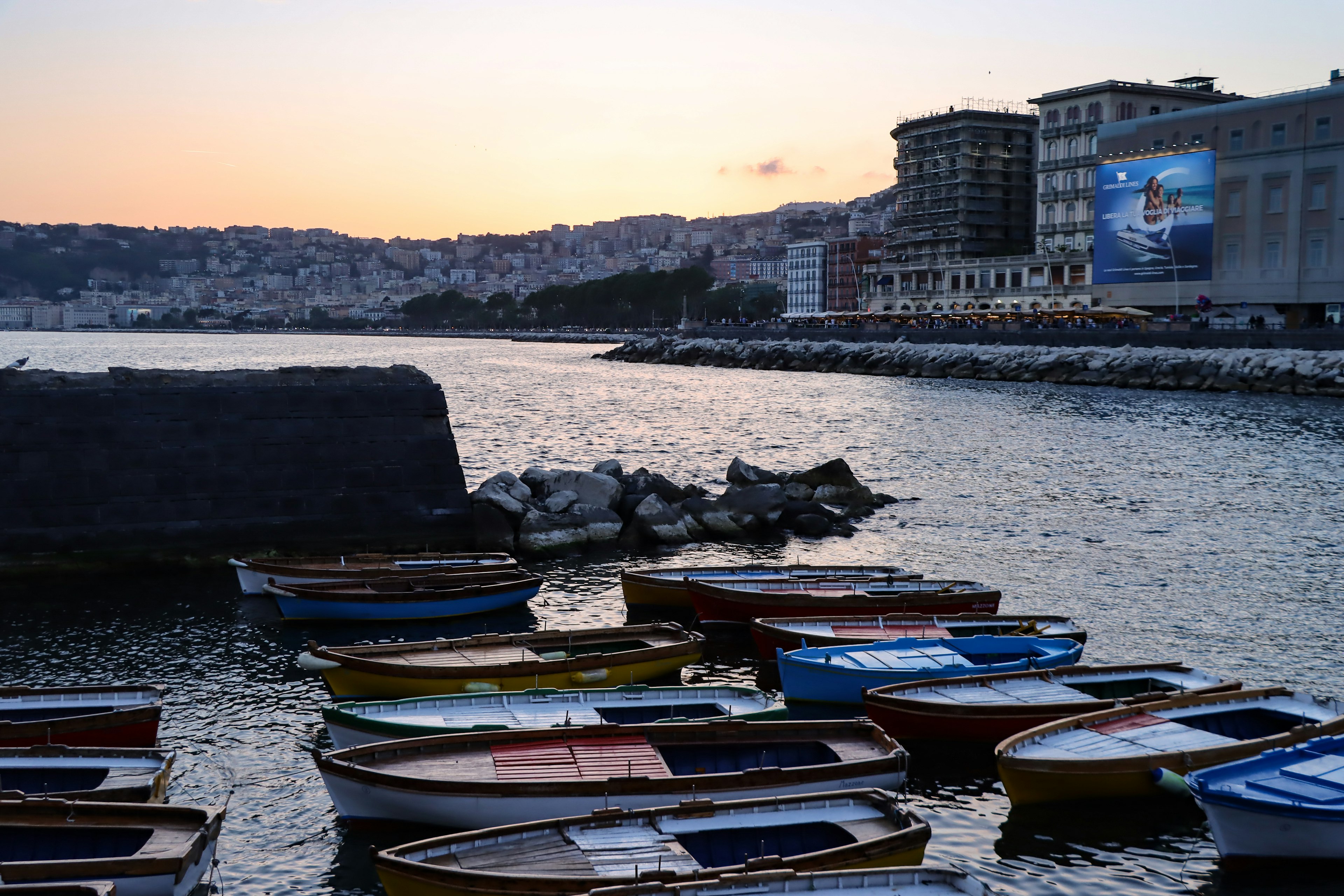 Colorful boats floating on the sea at sunset with a harbor view