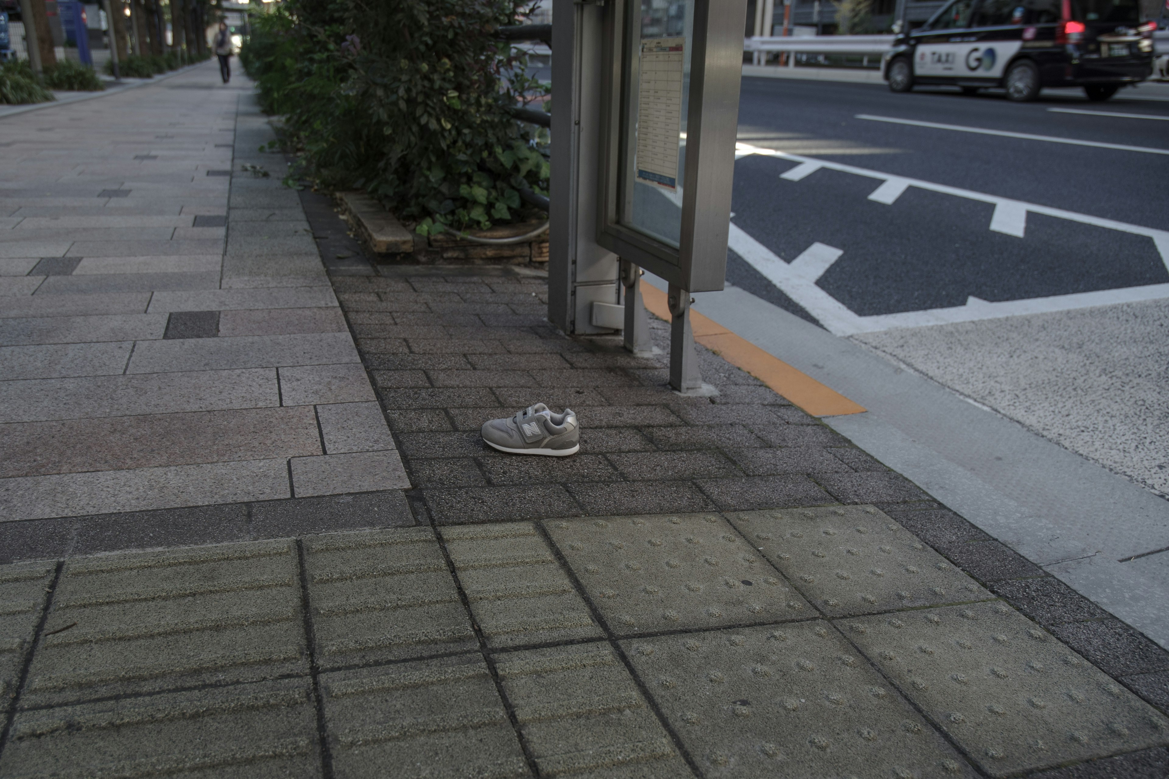 Une chaussure laissée sur le trottoir près d'une cabine téléphonique