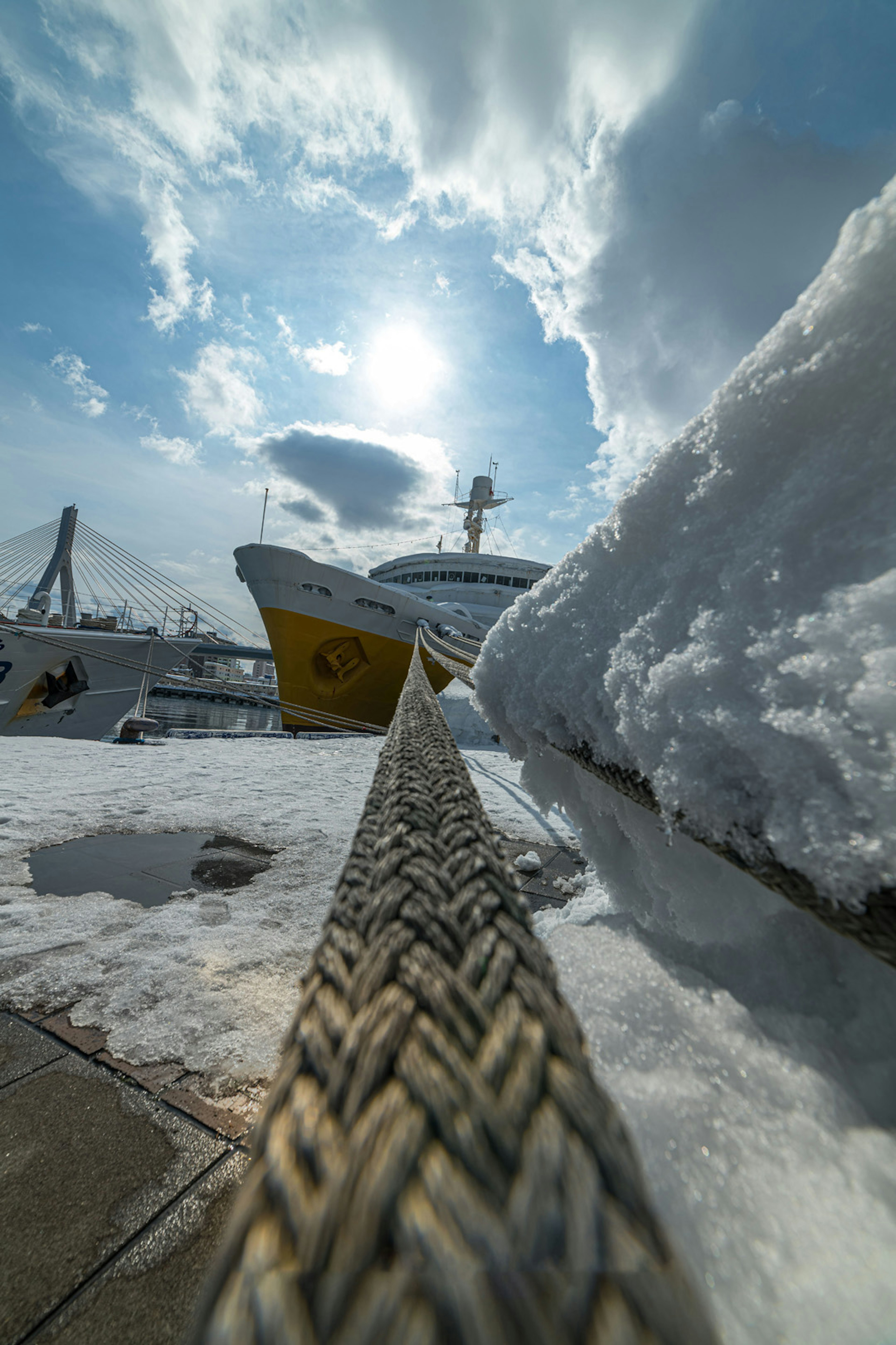 Rope of a boat covered in snow under a bright blue sky