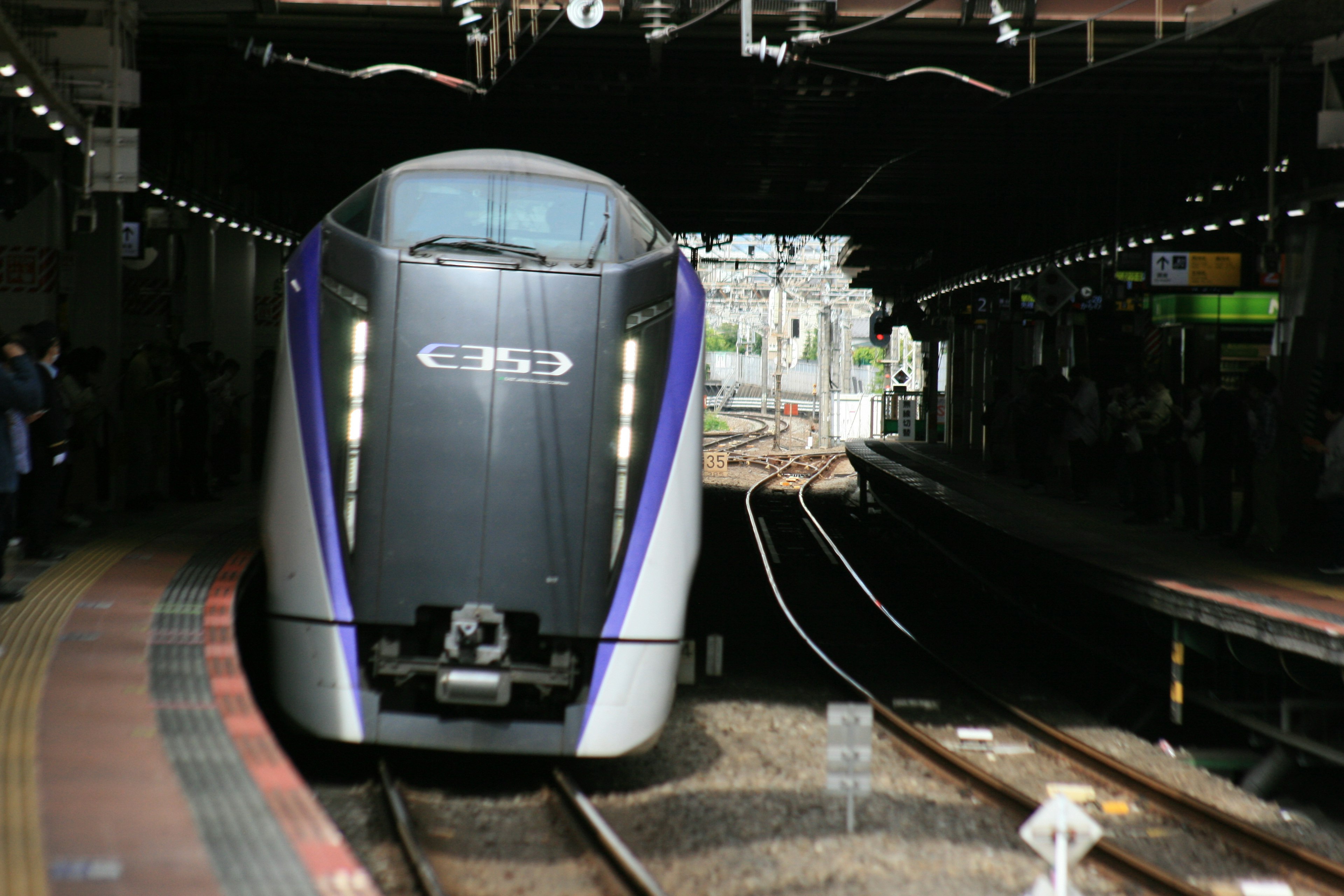 Ein eleganter Shinkansen-Zug mit lila Akzenten, der an einem Bahnhof ankommt