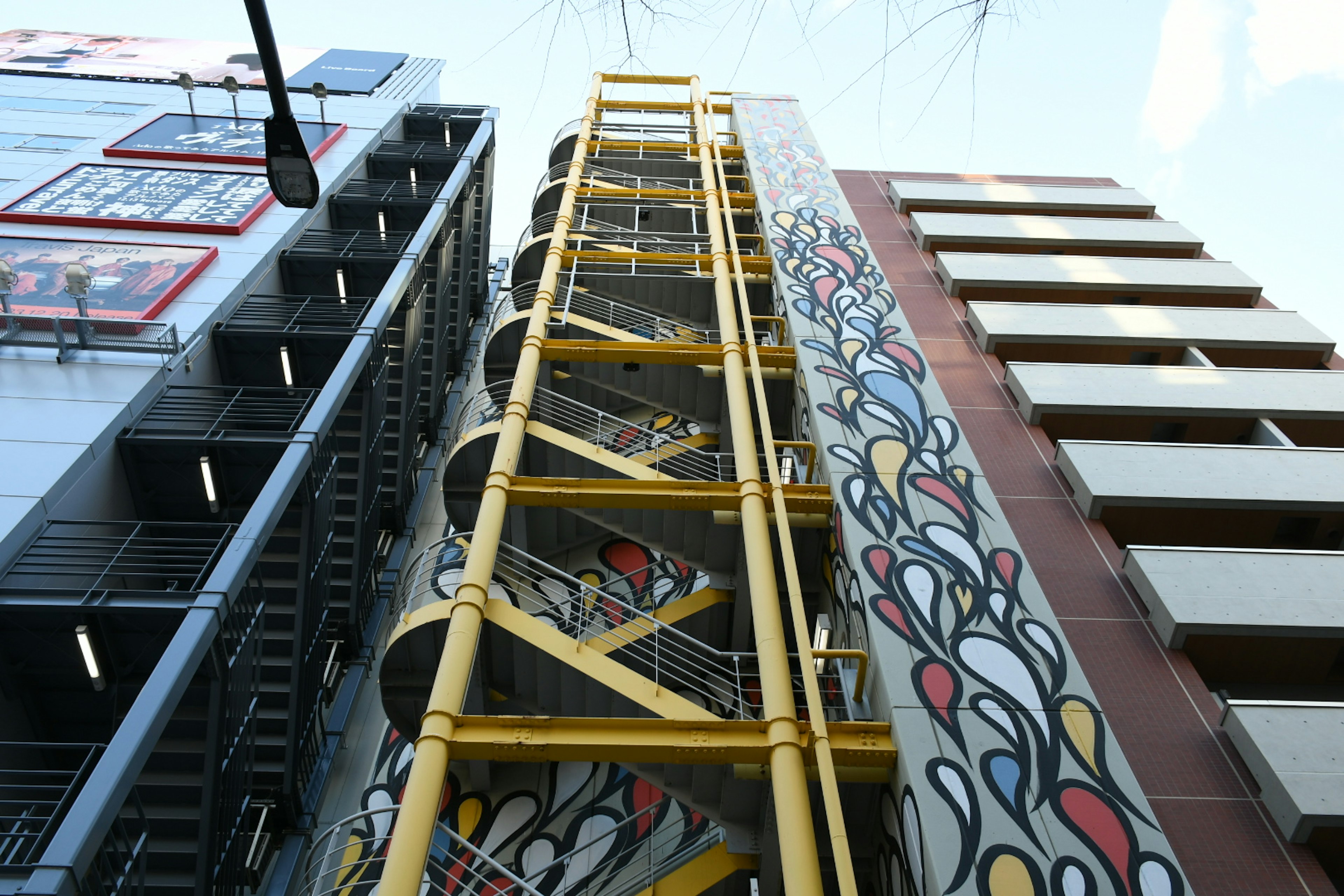 Edificio con scala a chiocciola gialla e murale colorato