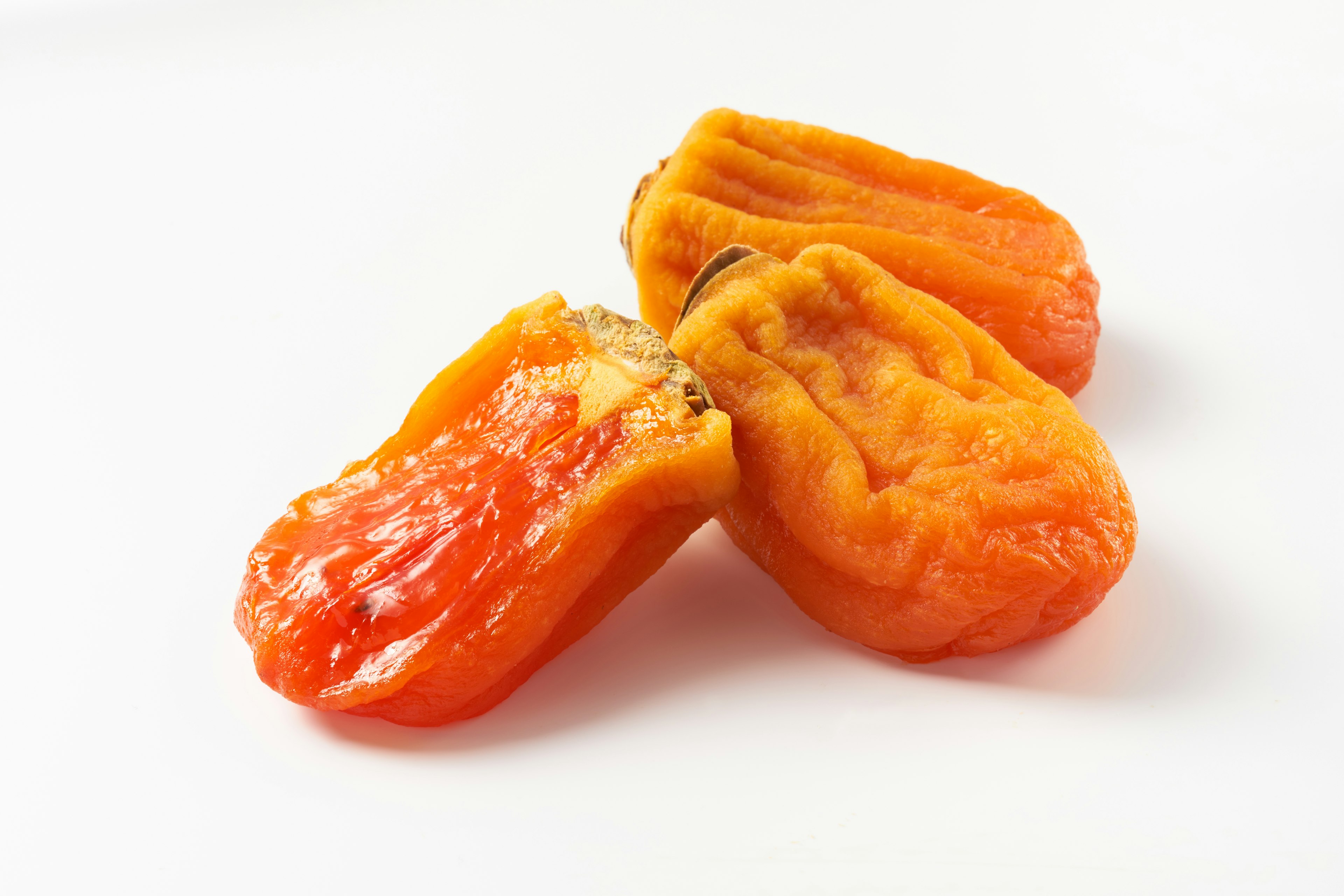 Dried orange fruit pieces arranged on a white background