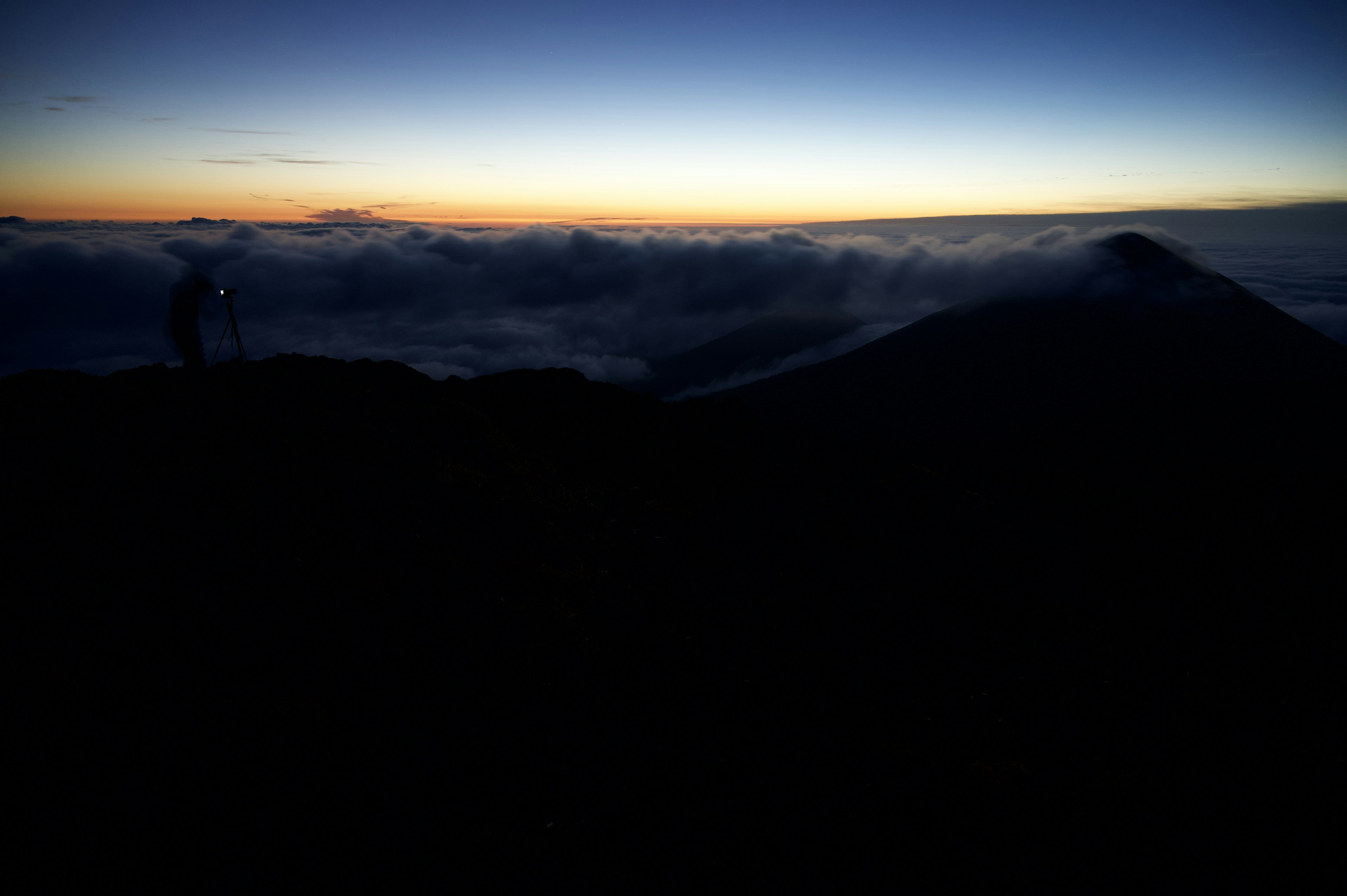 Paysage de l'aube depuis un sommet de montagne silhouette d'une personne et mer de nuages