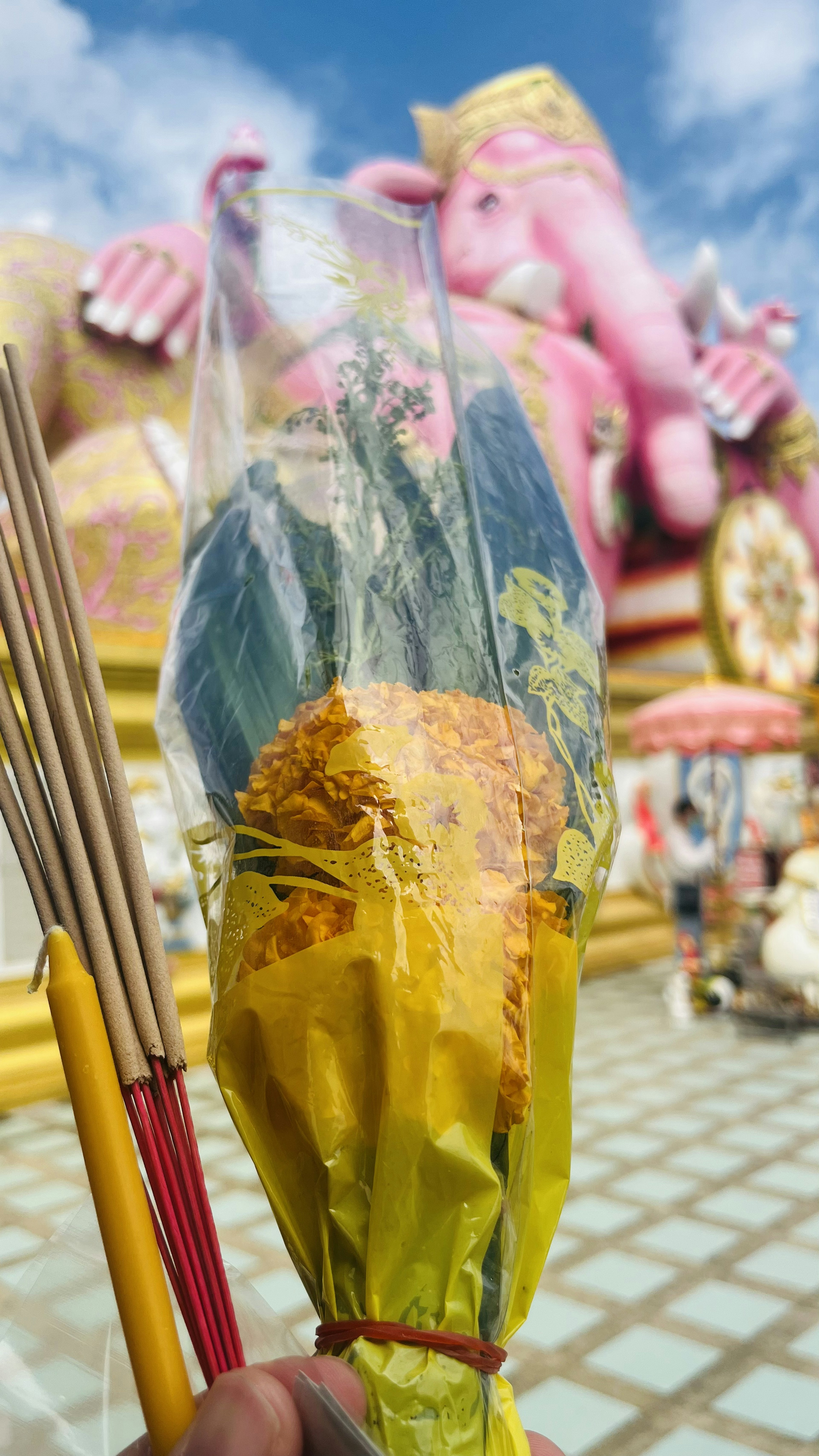 Ein in der Hand gehaltenes Bouquet mit einer großen Ganesha-Statue im Hintergrund