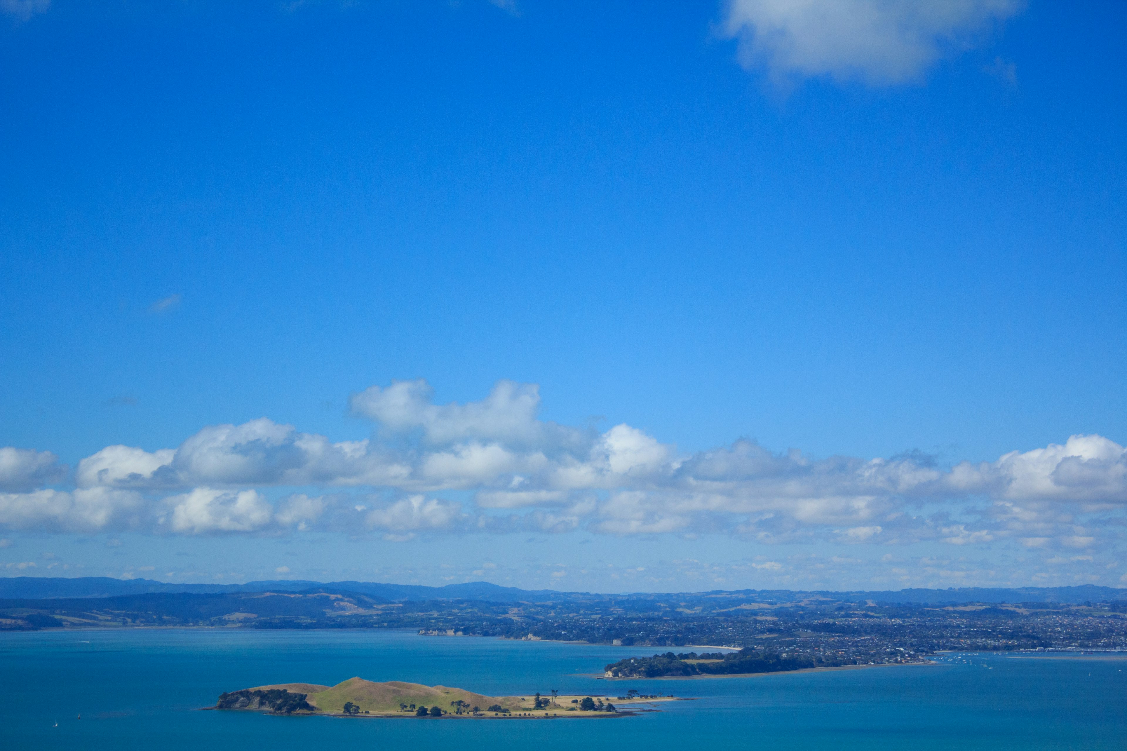 Landschaftsansicht einer Insel umgeben von türkisfarbenem Wasser unter blauem Himmel