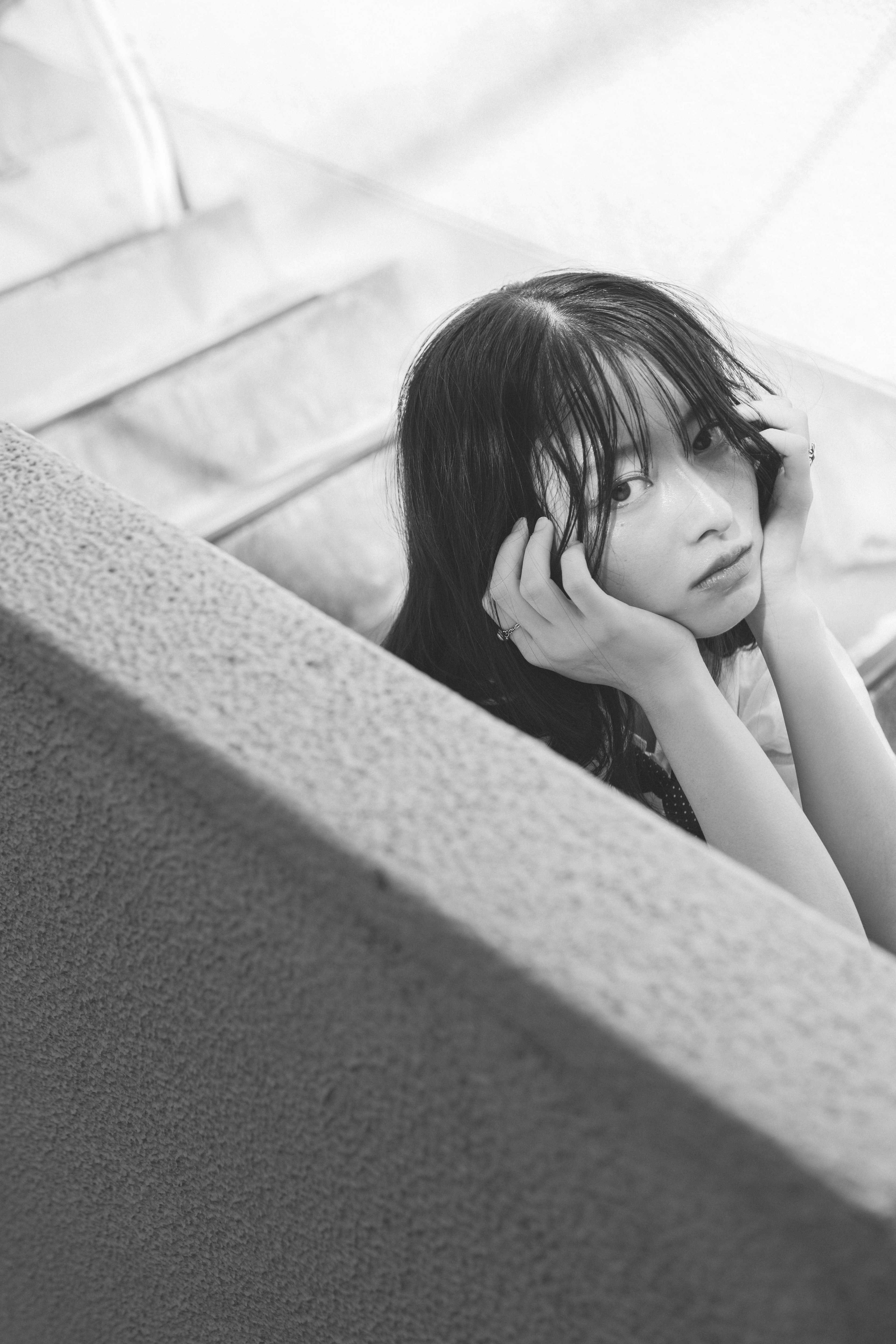 Black and white photo of a woman leaning against a staircase