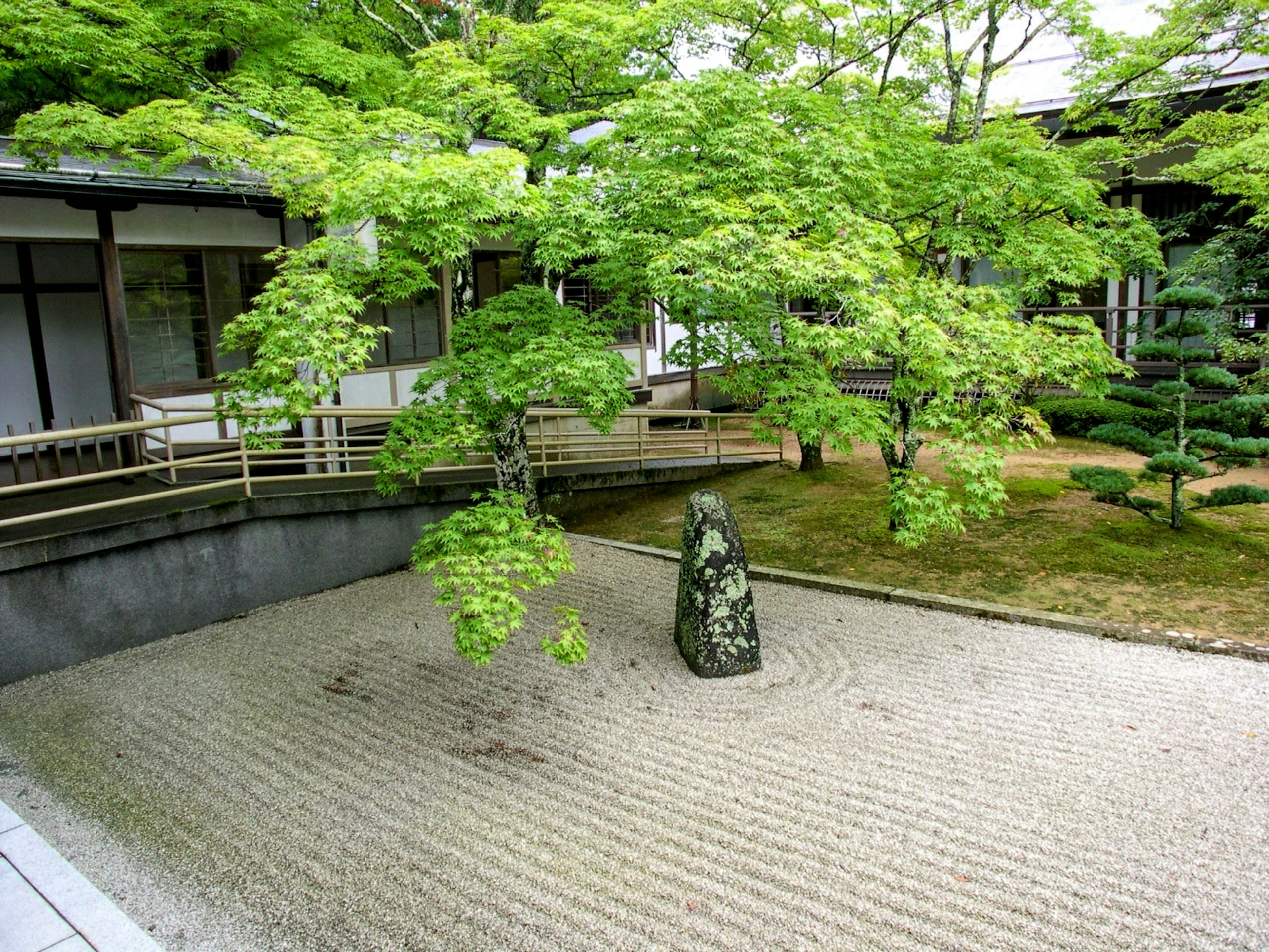 A serene garden featuring a stone and lush trees