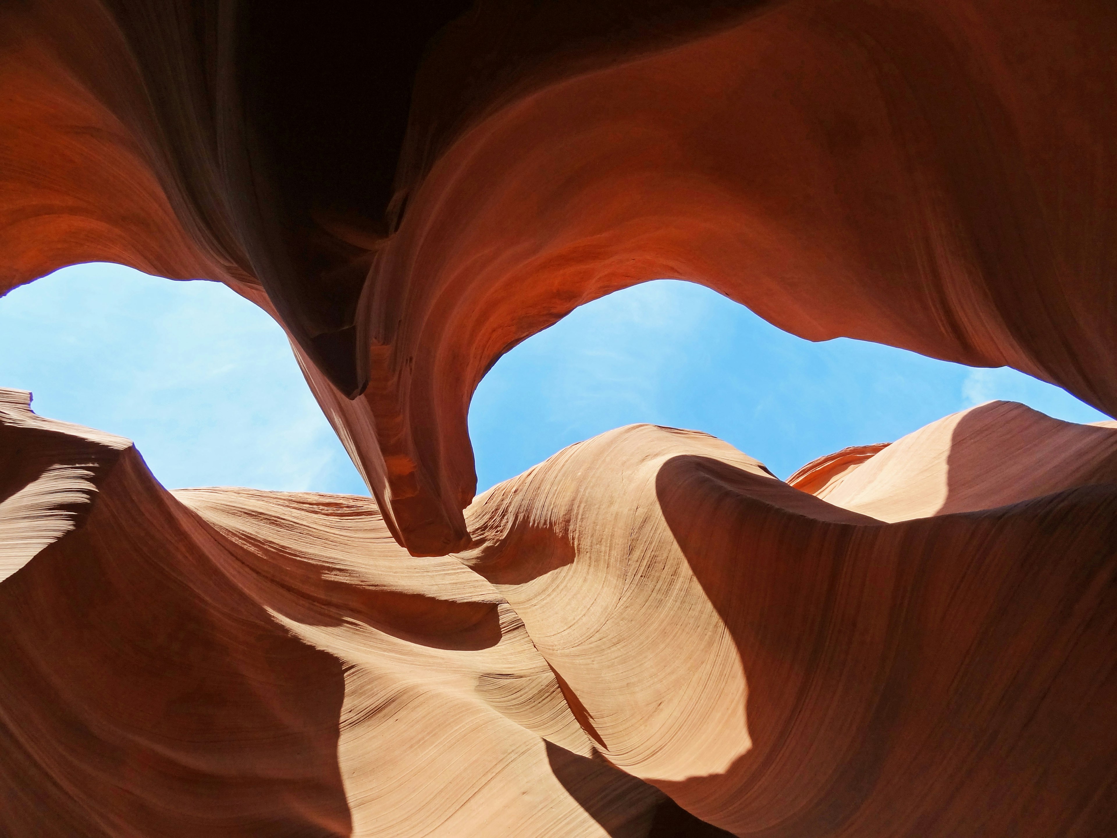 View of Antelope Canyon showcasing curved red rock formations and blue sky