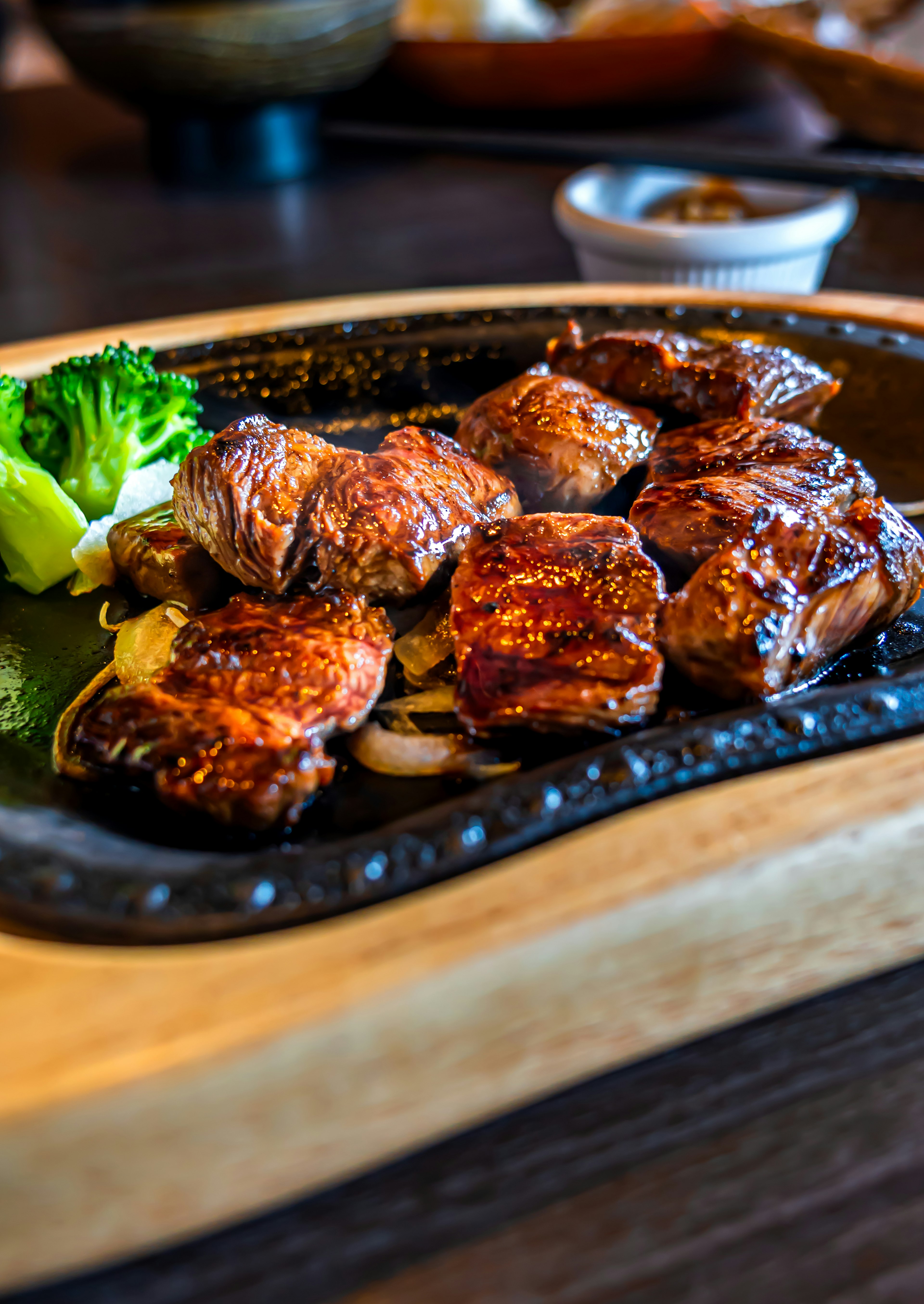 Grilled meat served on a sizzling plate with broccoli