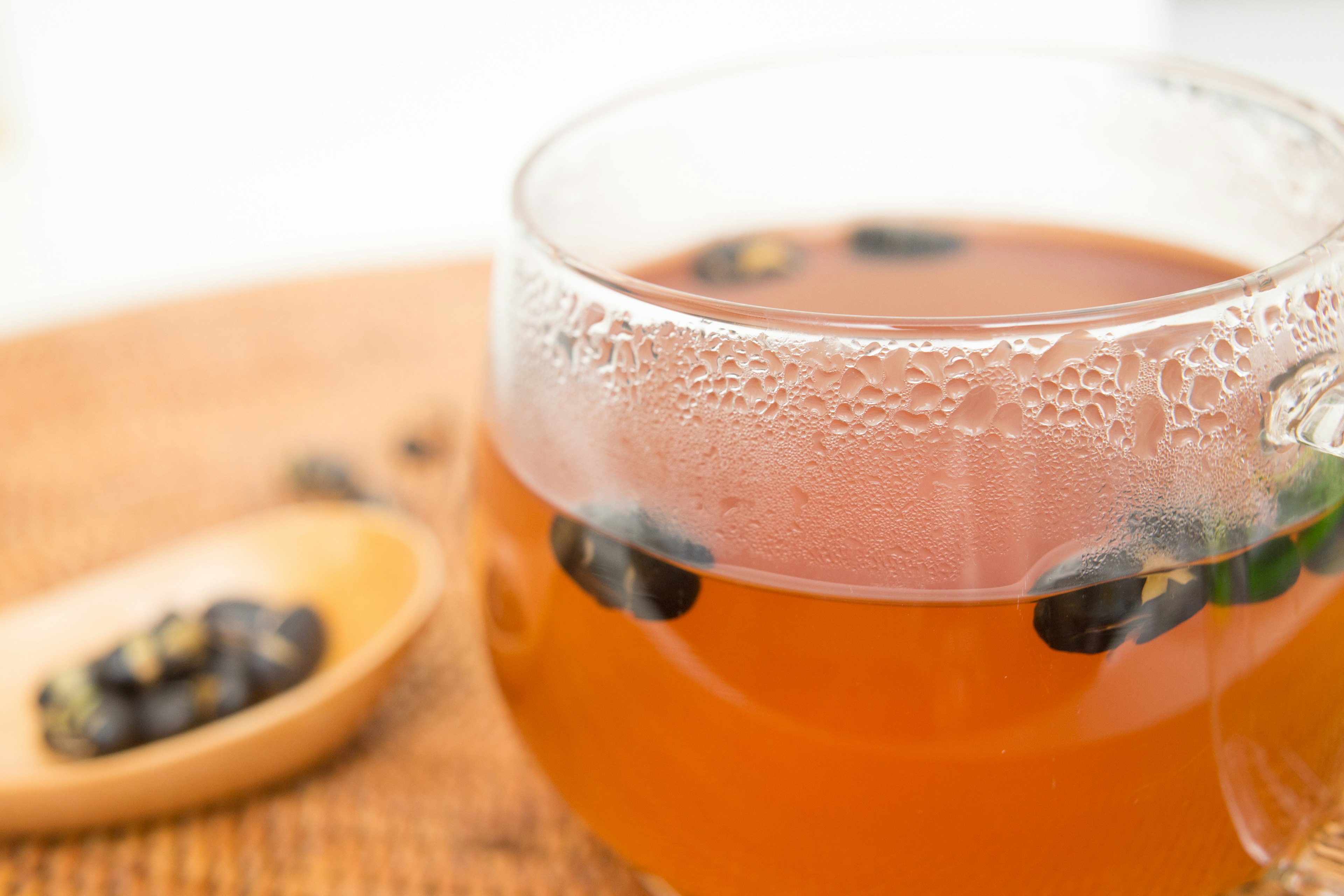 Tazza di vetro trasparente piena di tè e fagioli galleggianti