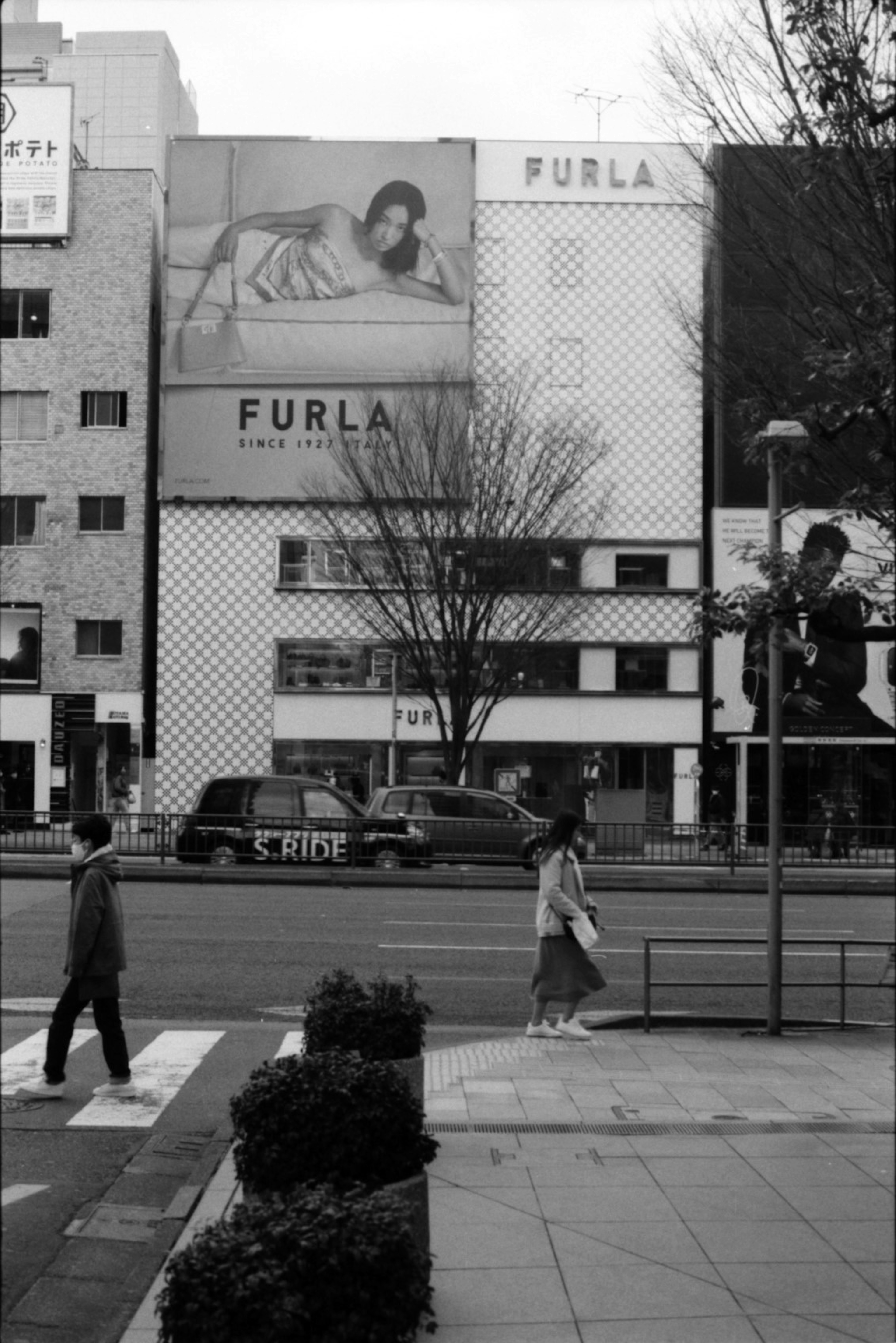 Scène urbaine en noir et blanc avec une publicité FURLA sur un bâtiment