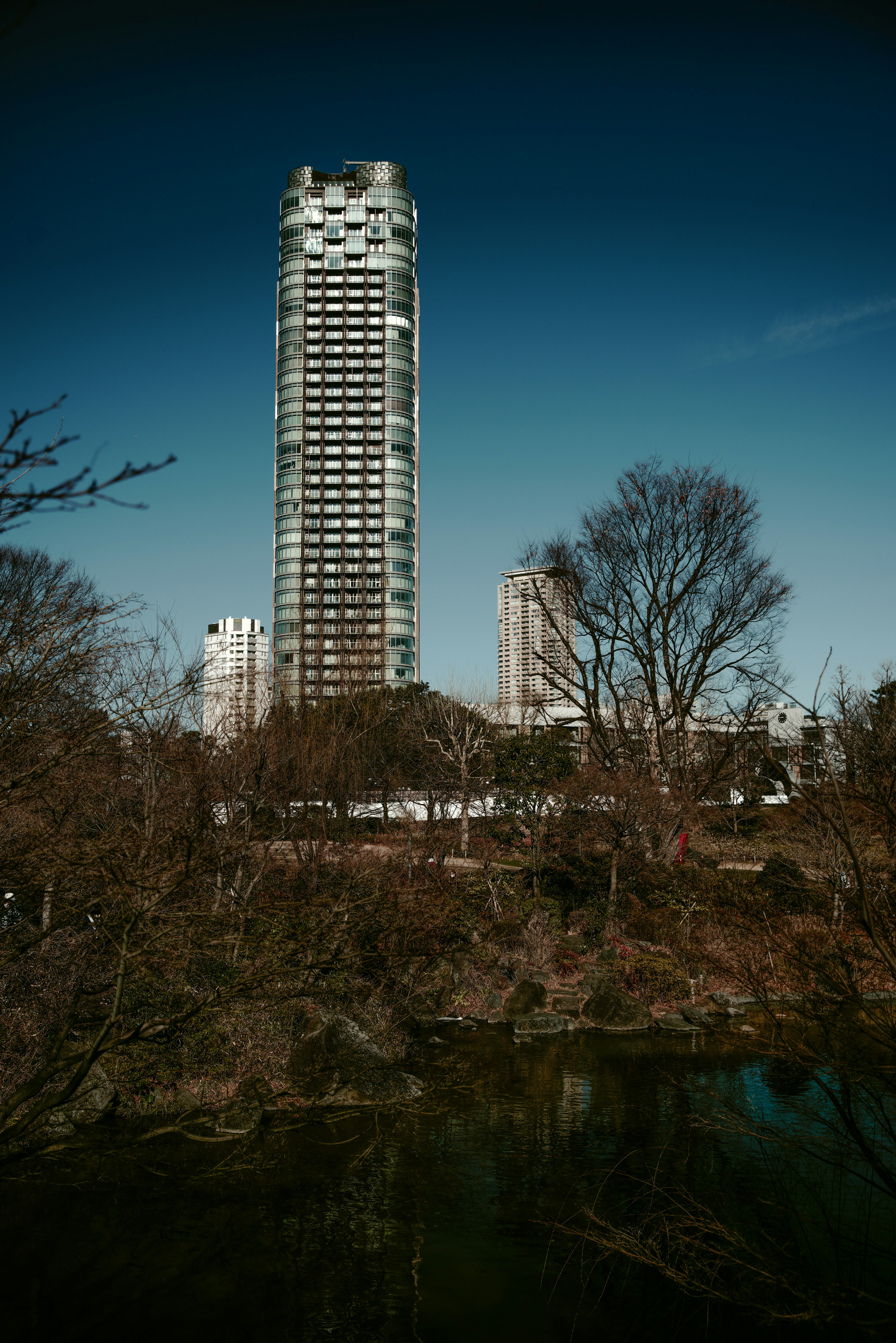 A tall building surrounded by trees and water