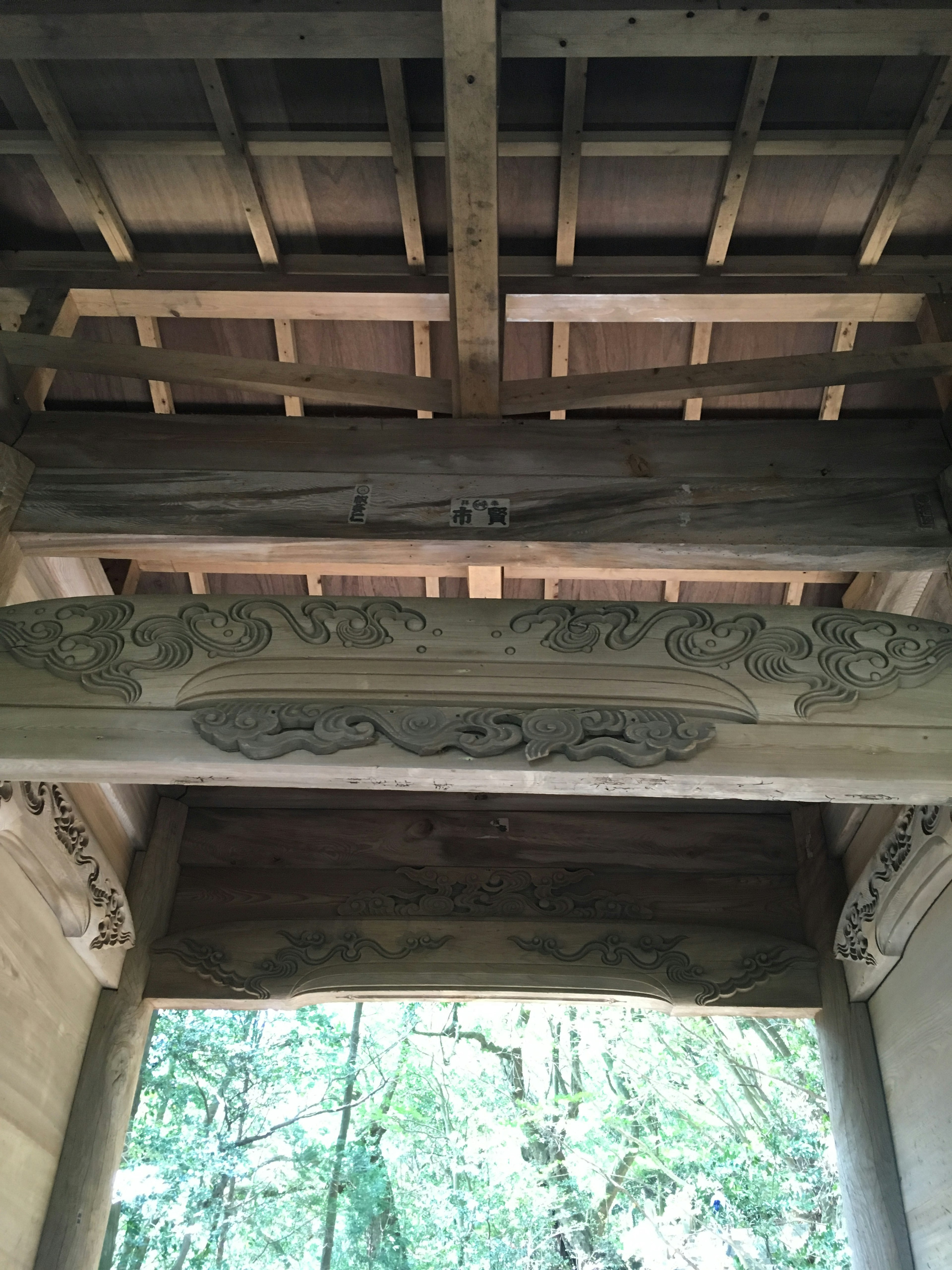 View from below a wooden roof featuring intricate carvings on the beam