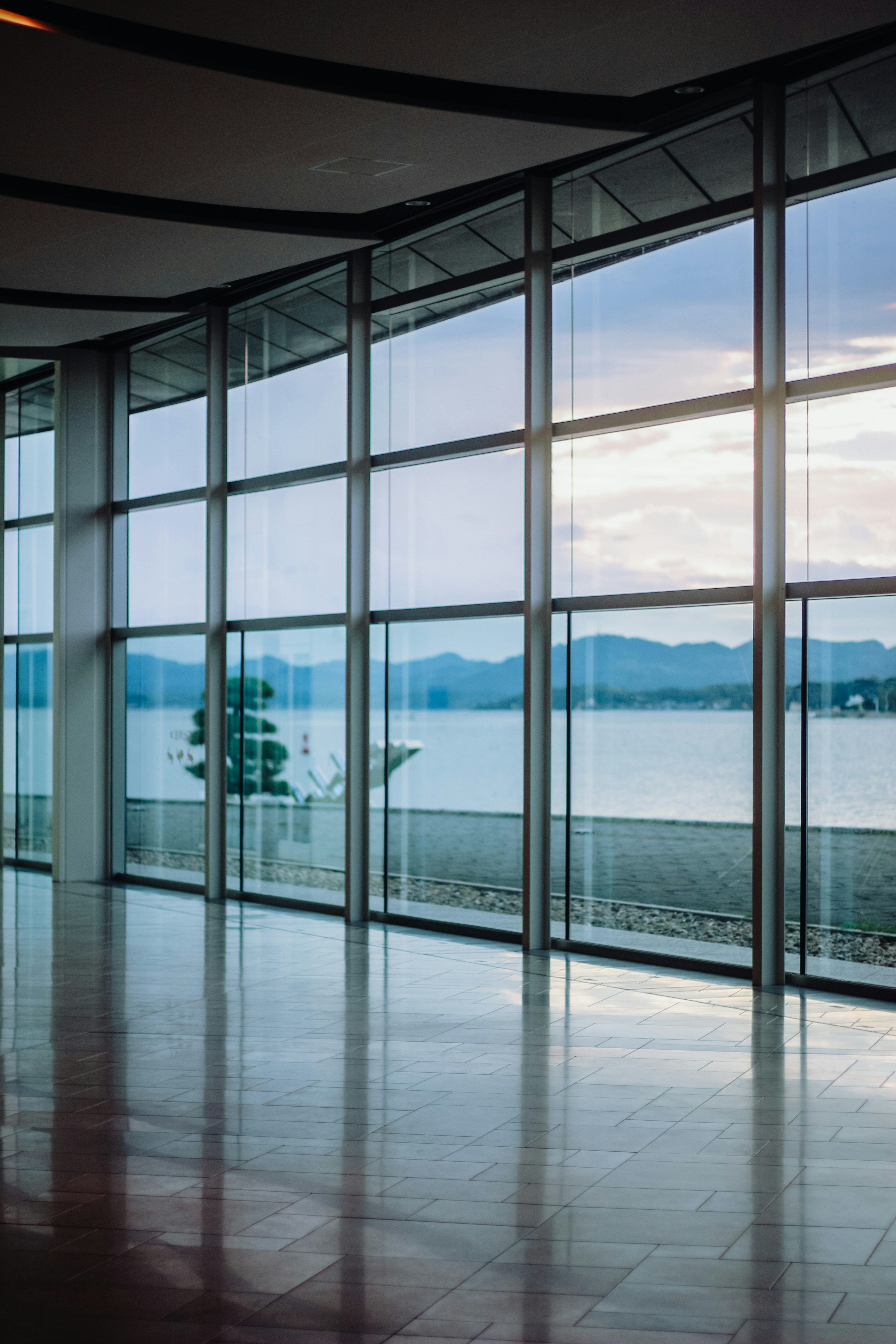 Modern interior with large glass windows showcasing a lake and mountain view