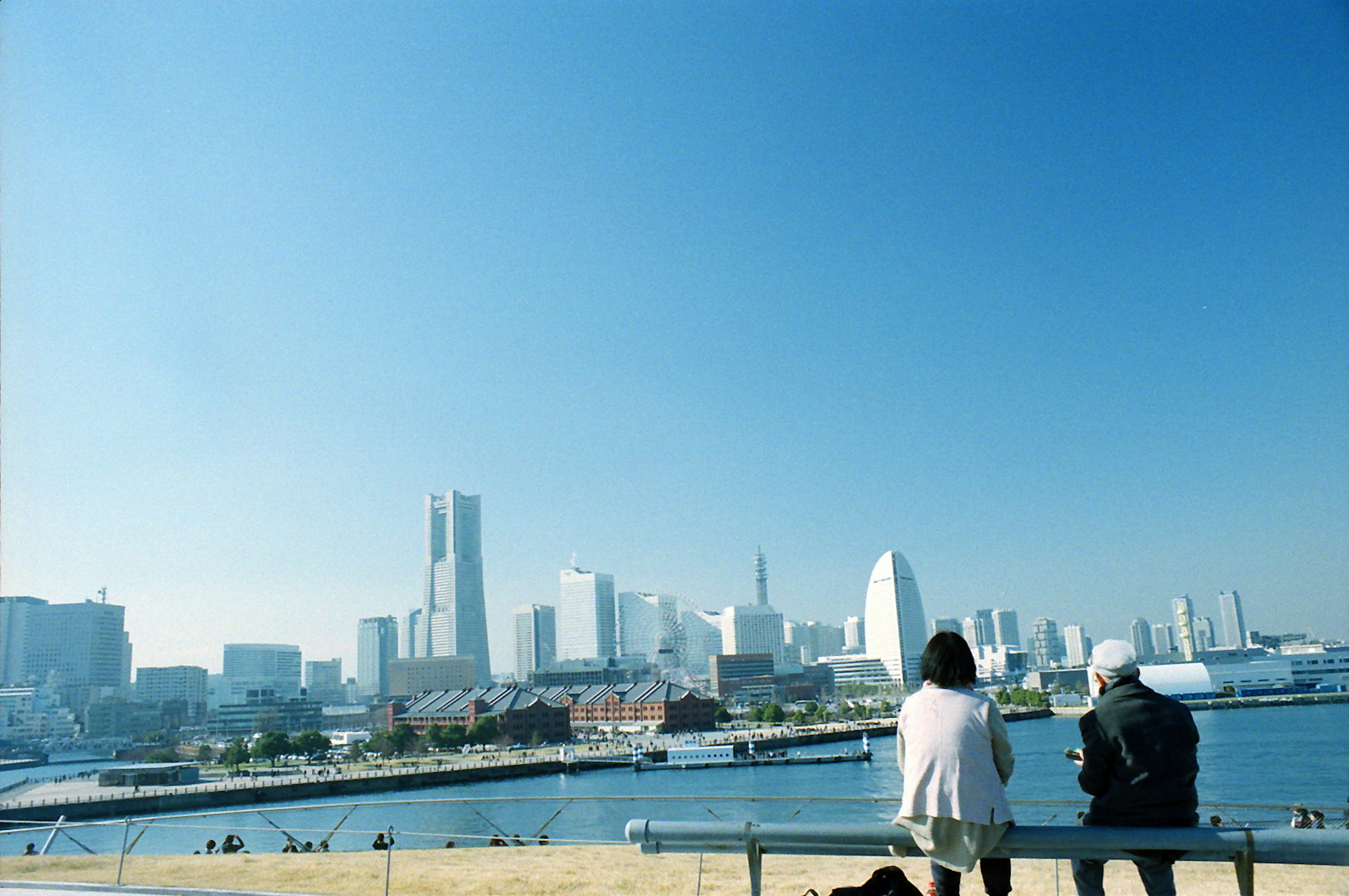 Zwei Personen, die die Aussicht an der Waterfront von Yokohama mit Wolkenkratzern im Hintergrund genießen