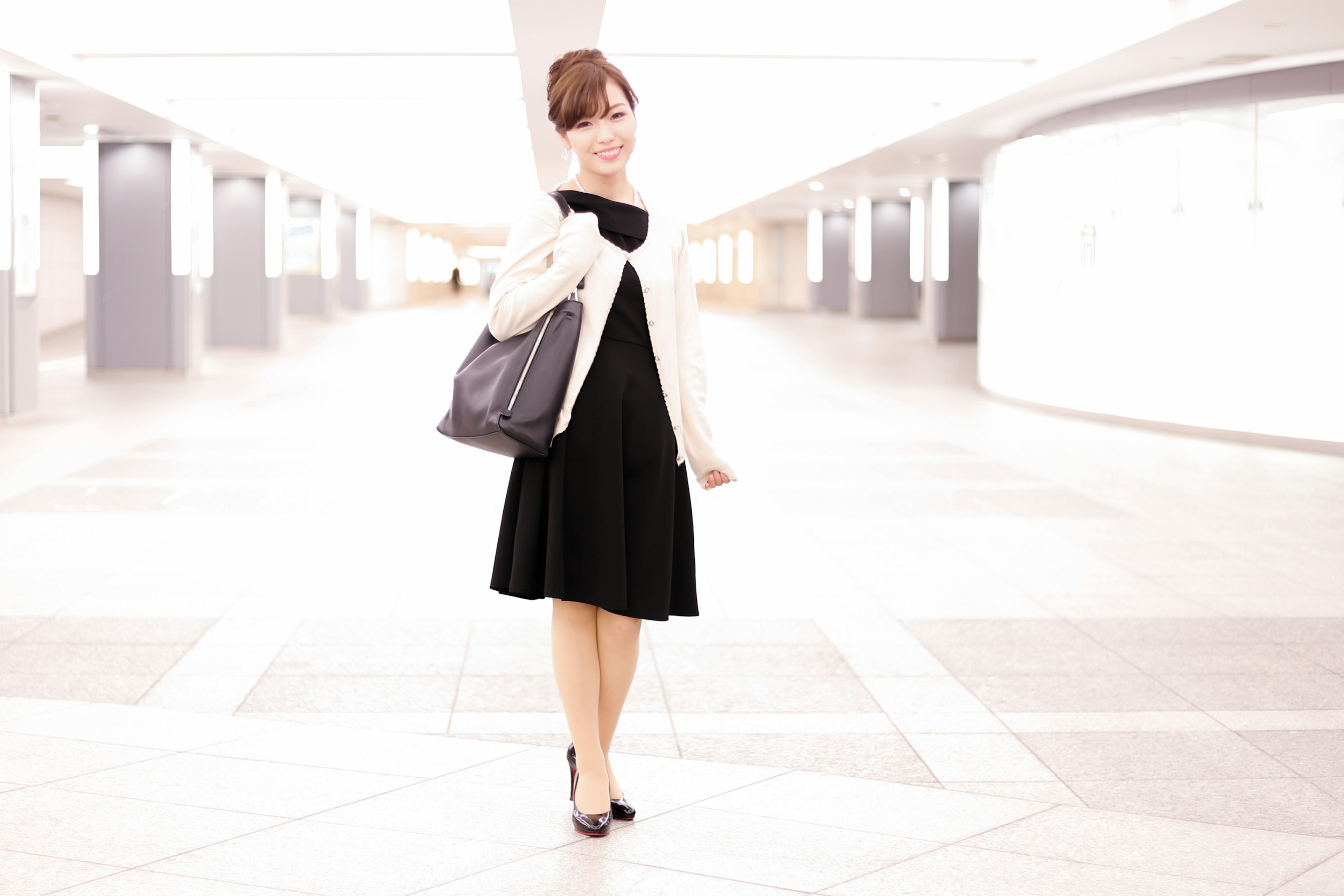 A woman in a black dress posing in a bright background