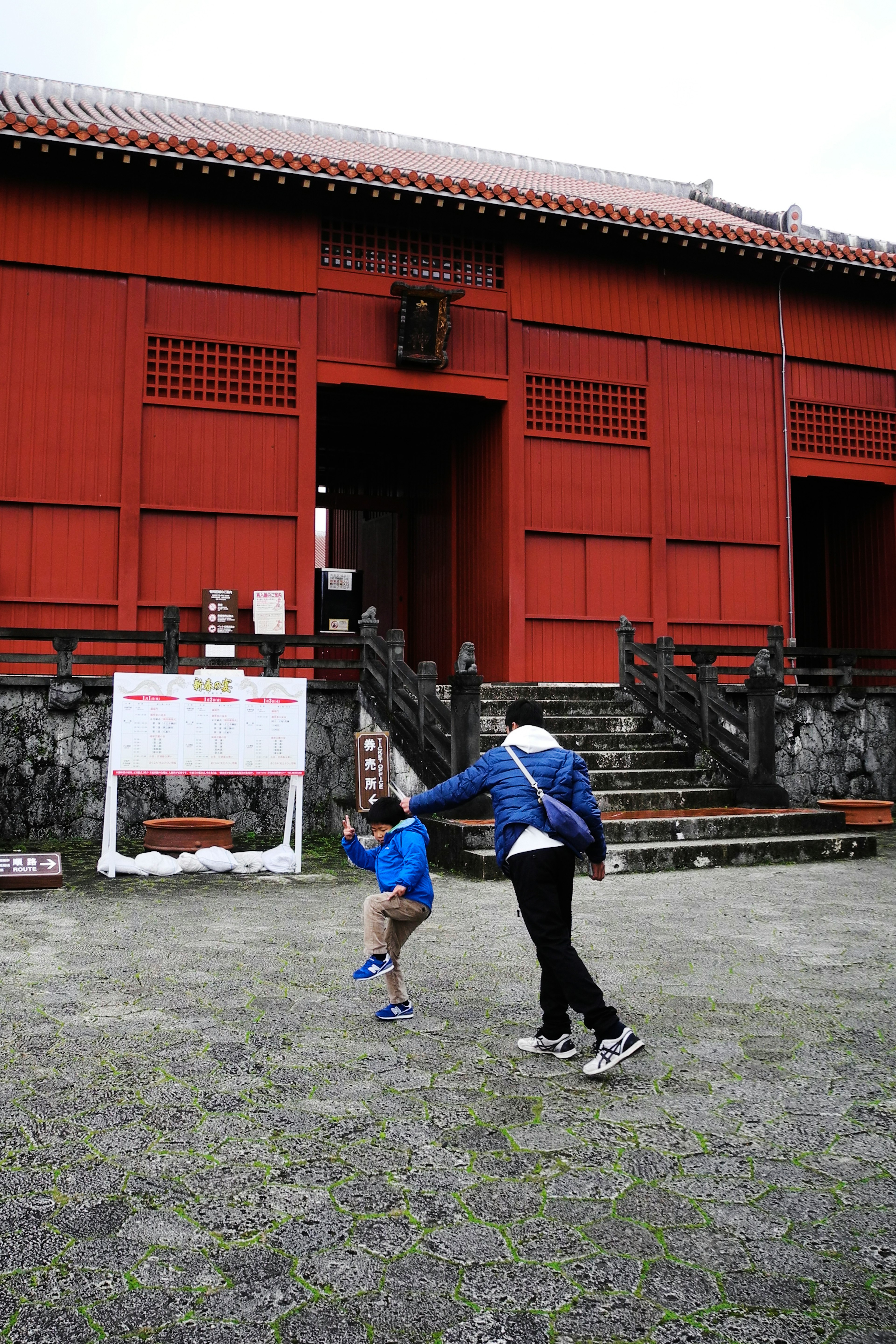 A child and an adult playing in front of a red building