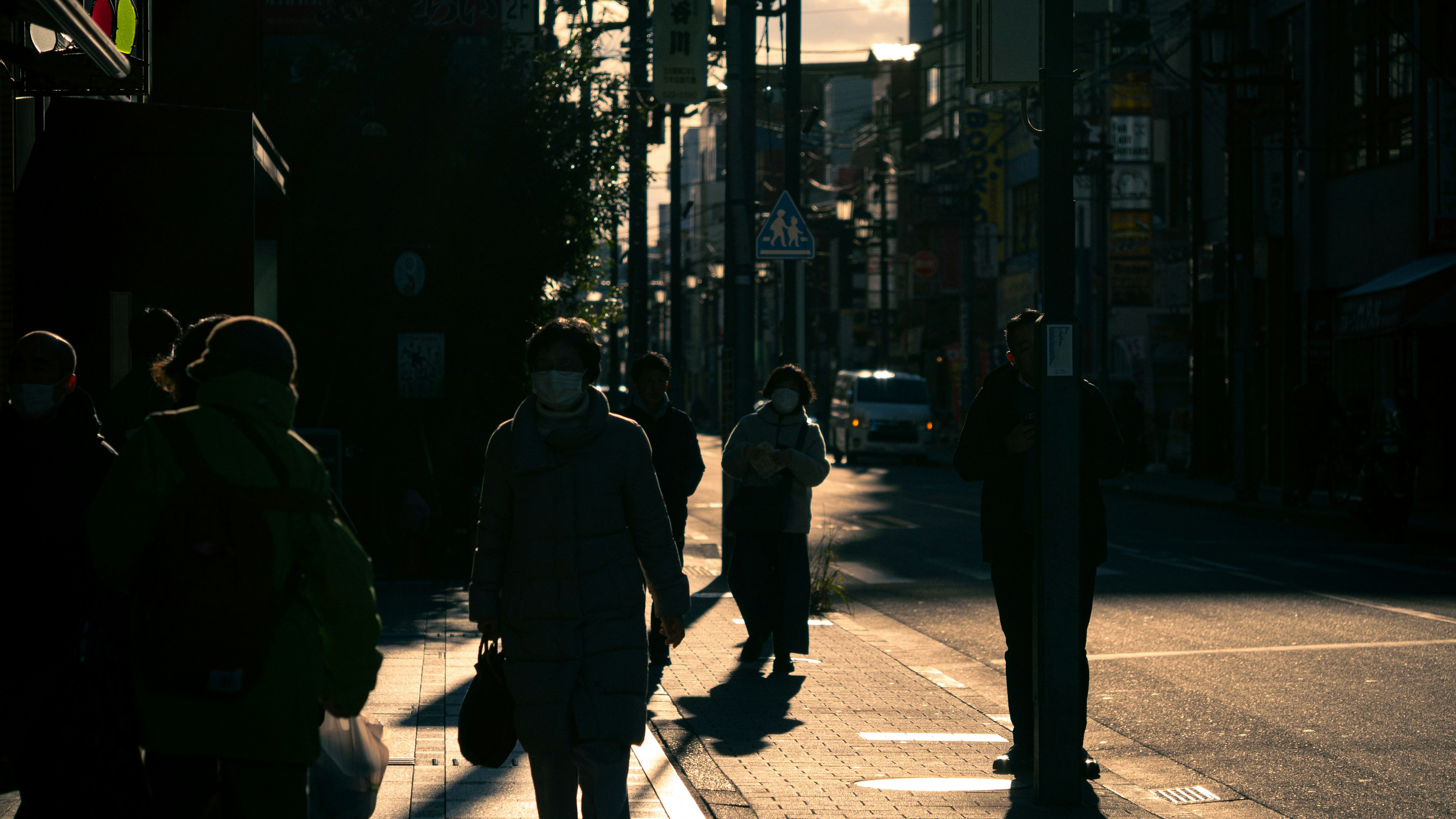 Silhouette di persone che camminano in una strada cittadina al tramonto