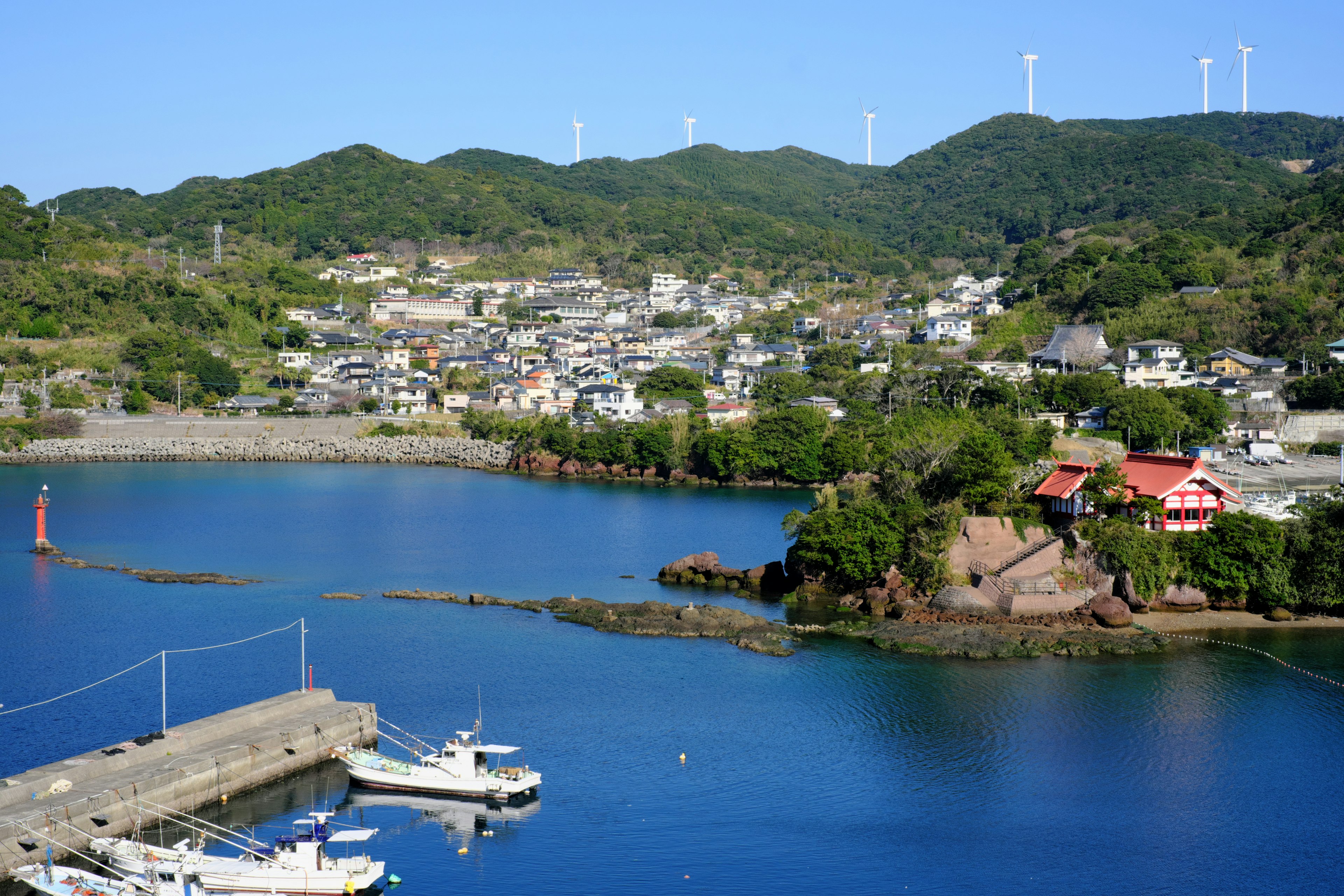 Vista escénica de un tranquilo pueblo costero rodeado de mar azul y colinas verdes