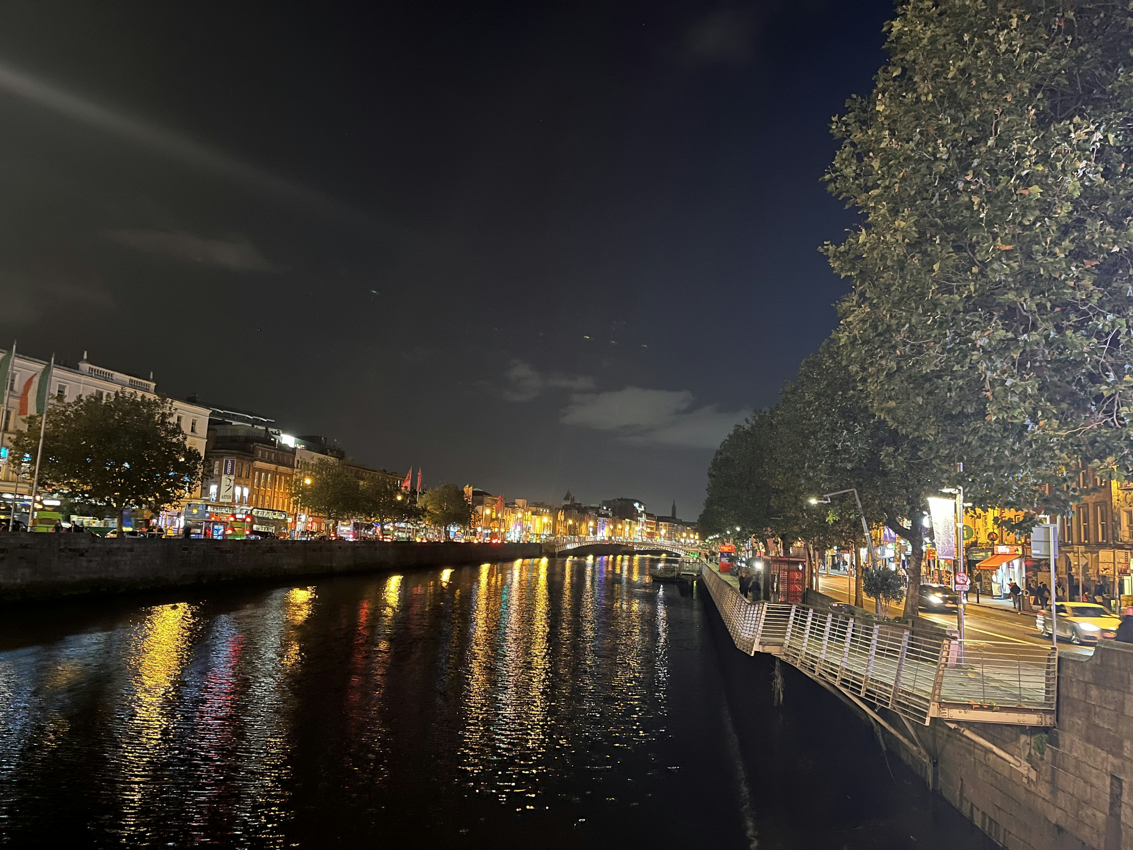 Nighttime view of a riverside cityscape with lights reflecting on the water