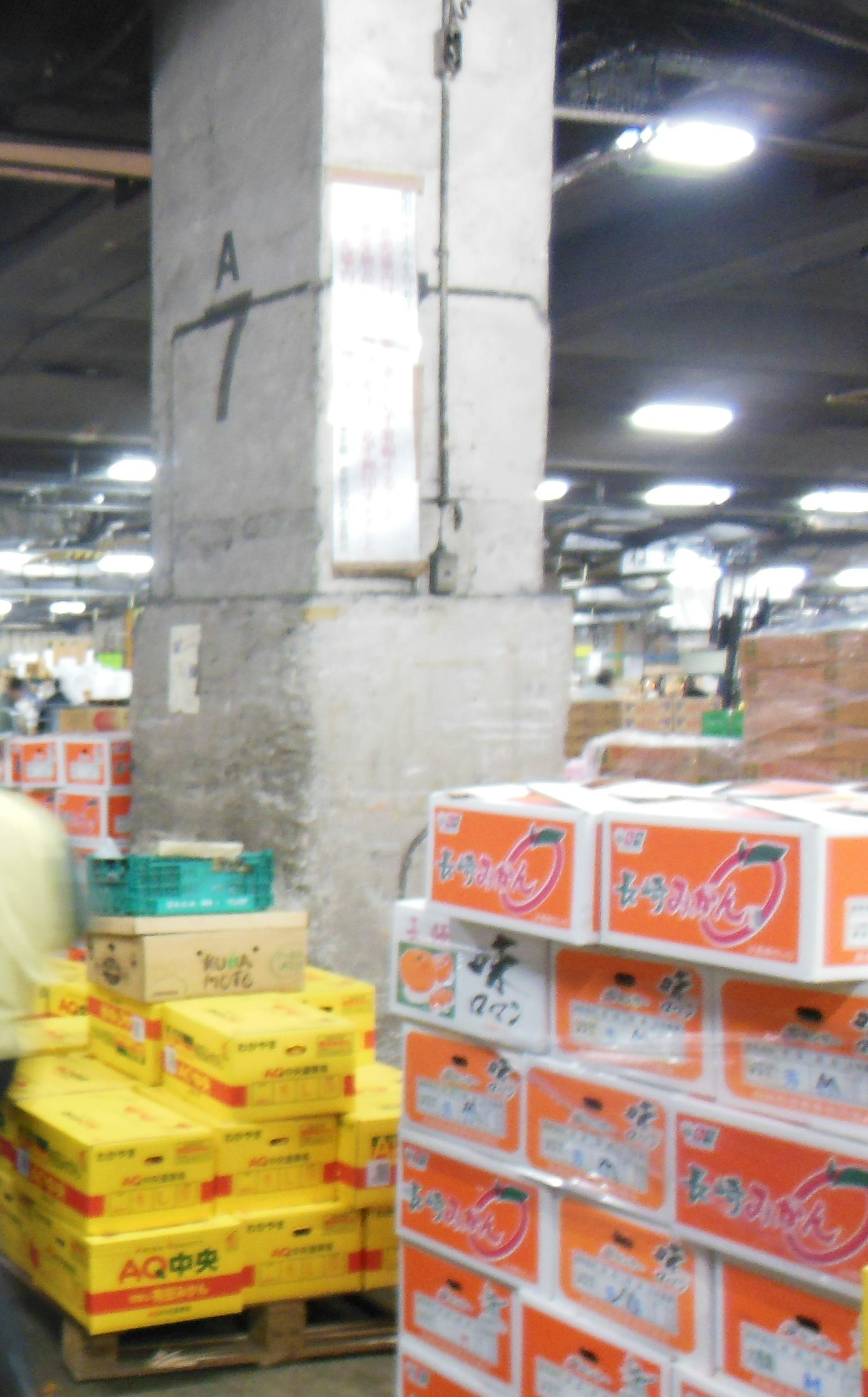 Warehouse interior featuring a concrete pillar and stacked orange and yellow boxes