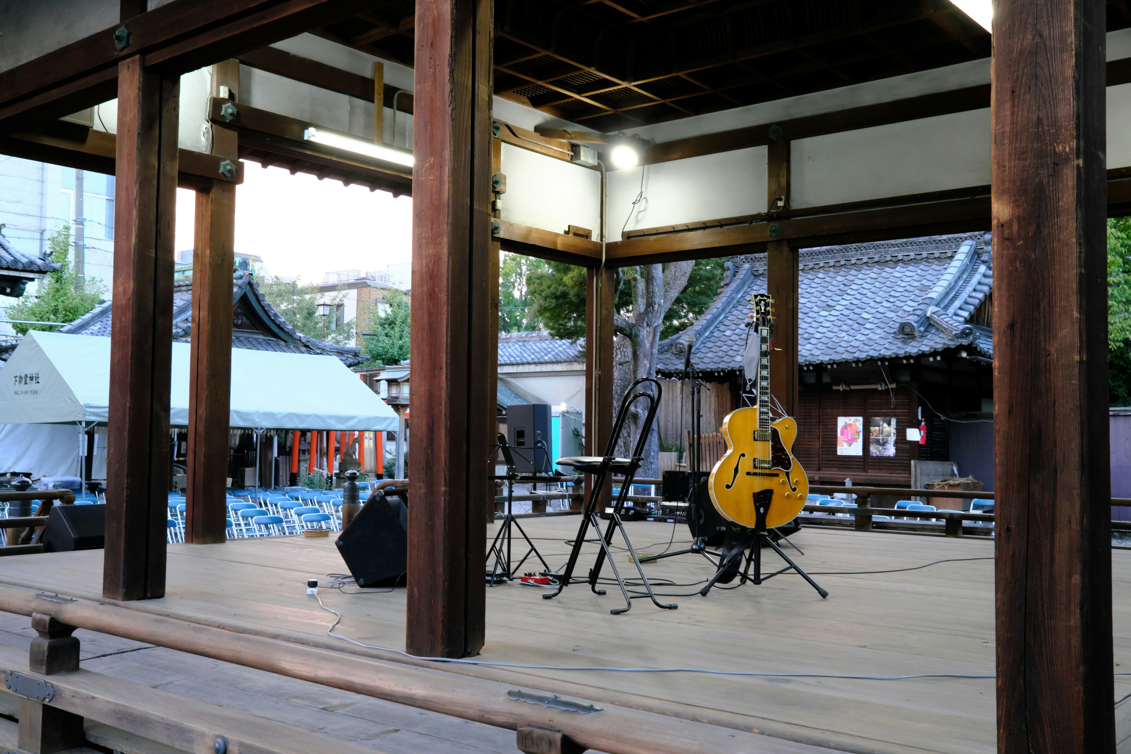 Escenario de madera con una guitarra grande y un micrófono