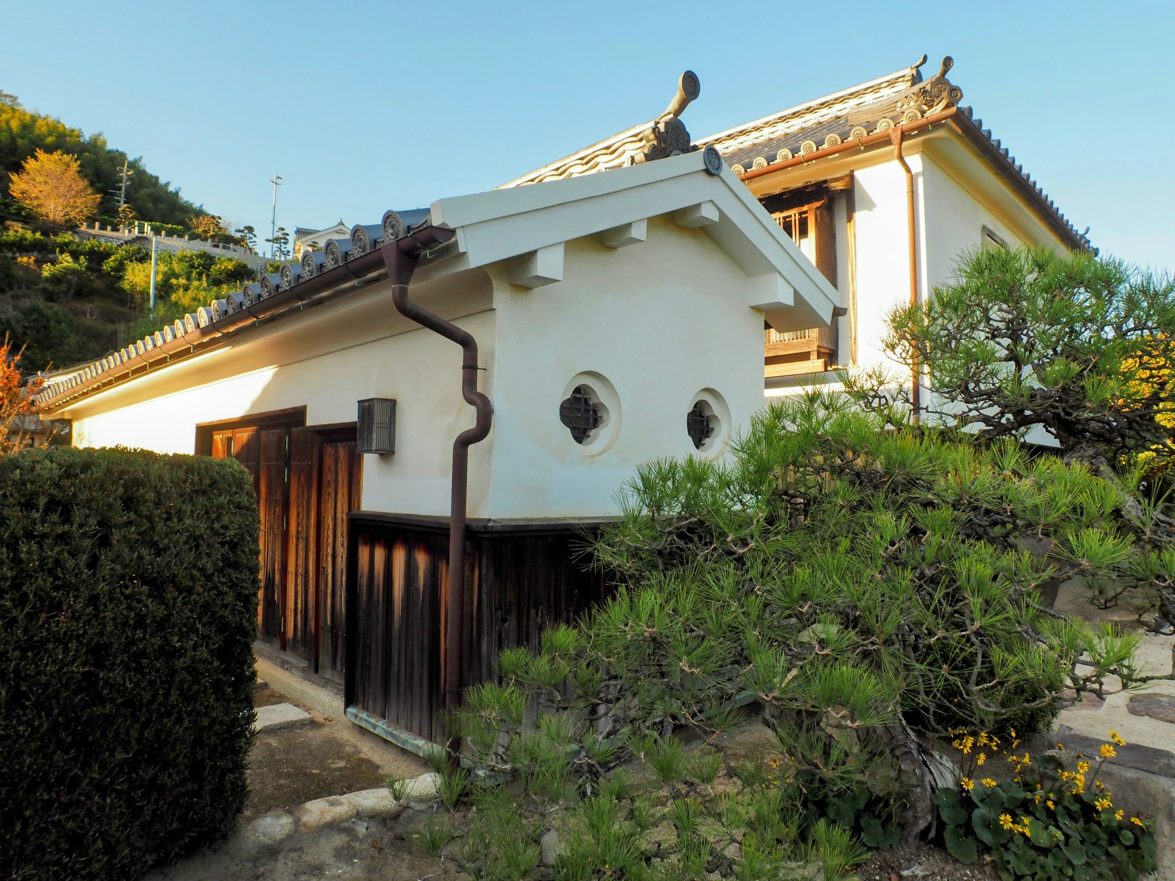 Eksterior rumah tradisional Jepang dengan taman subur dan pohon-pohon