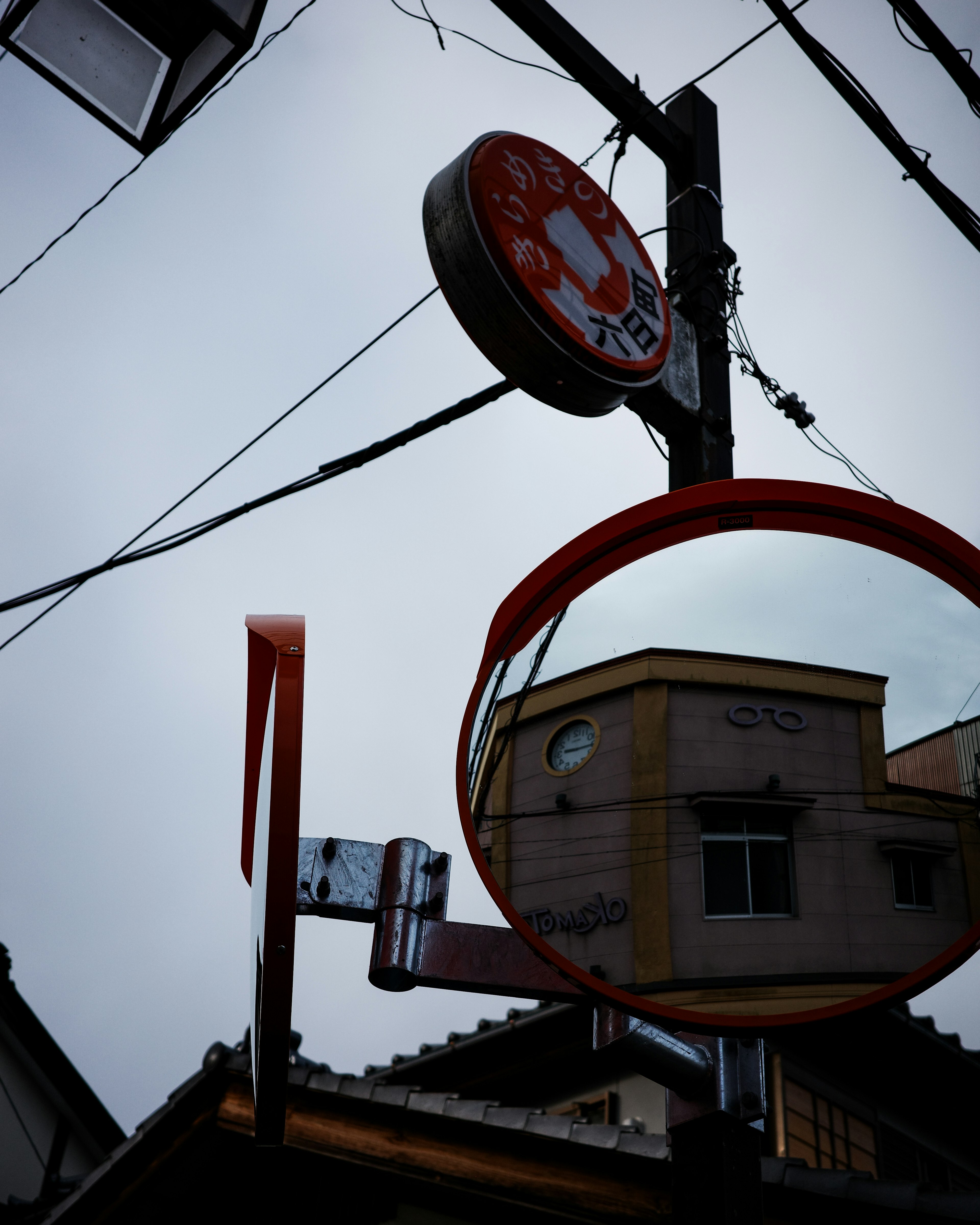 Street corner featuring a round red mirror and a building reflection