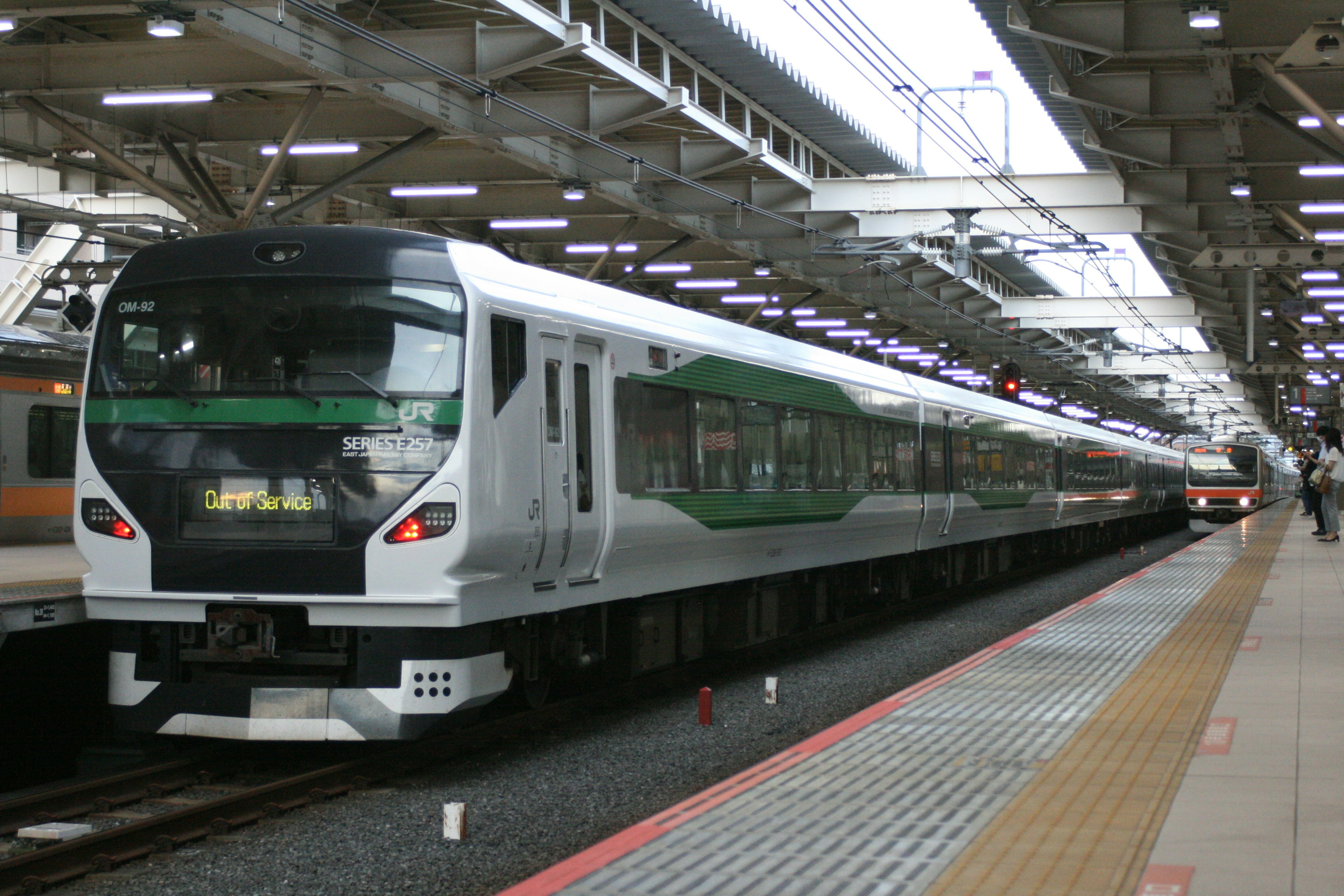 A white train is parked at a station with bright overhead lighting