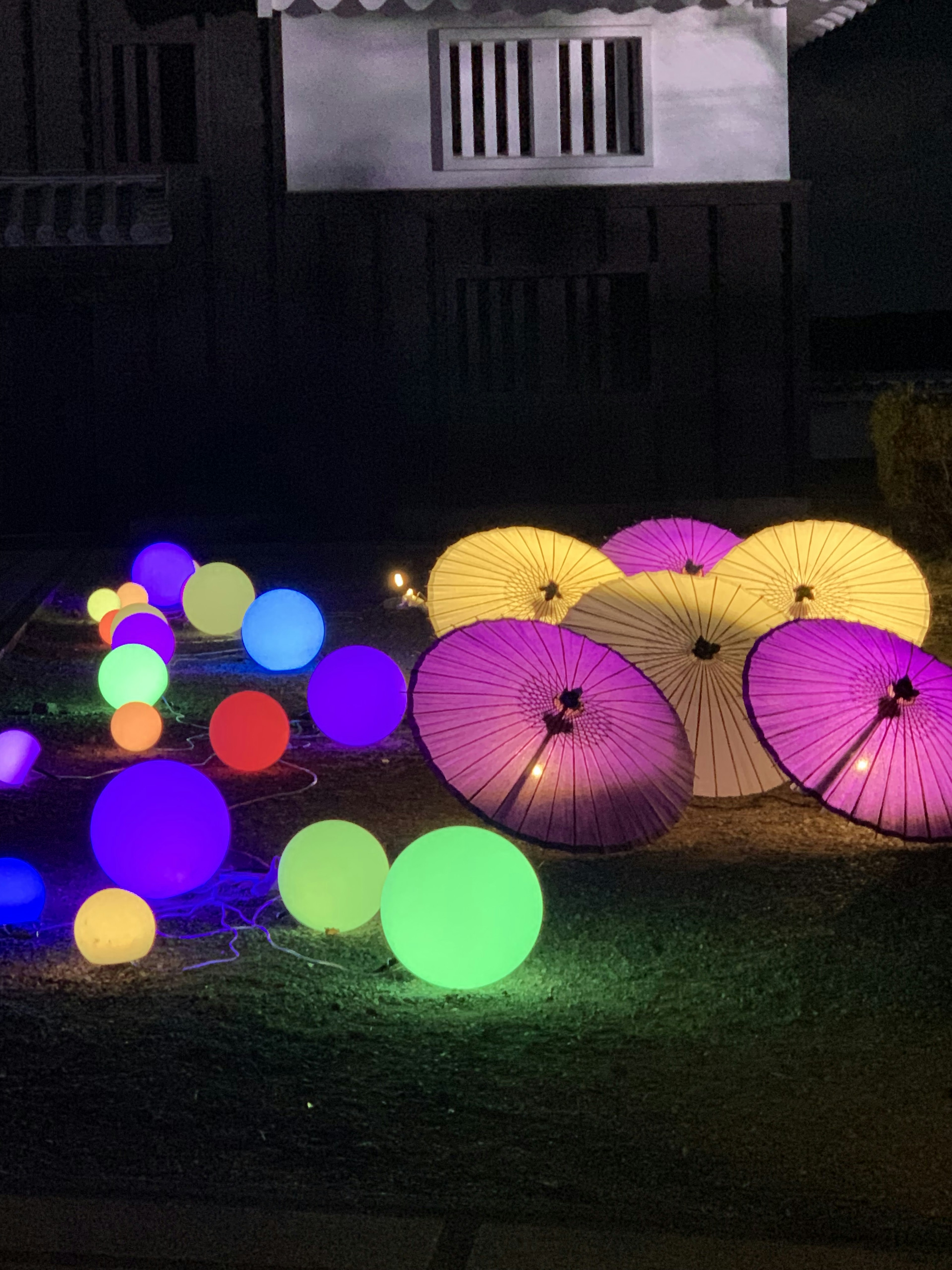 Linternas coloridas y esferas brillantes en un jardín nocturno