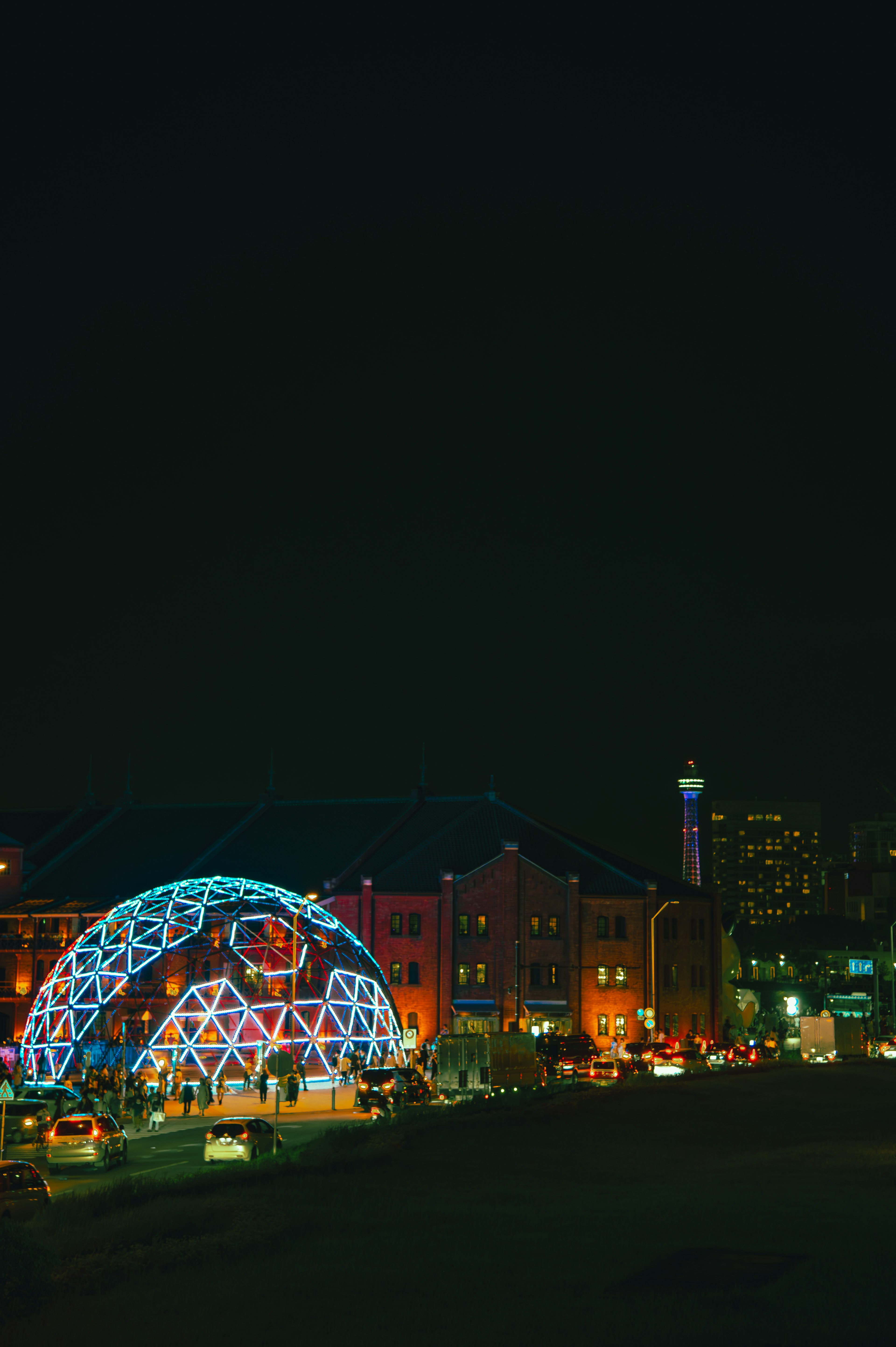 Paysage urbain nocturne avec une structure en dôme lumineuse et des bâtiments colorés