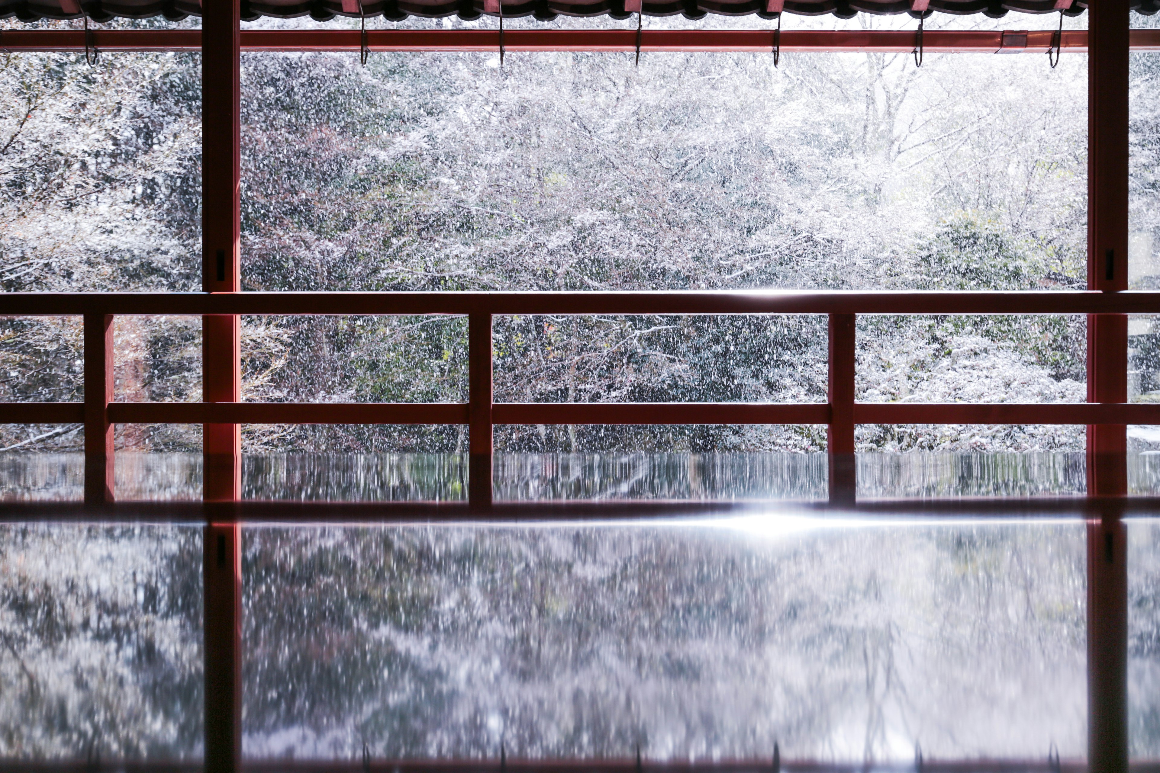 Interior view with red railing reflecting a serene Japanese landscape