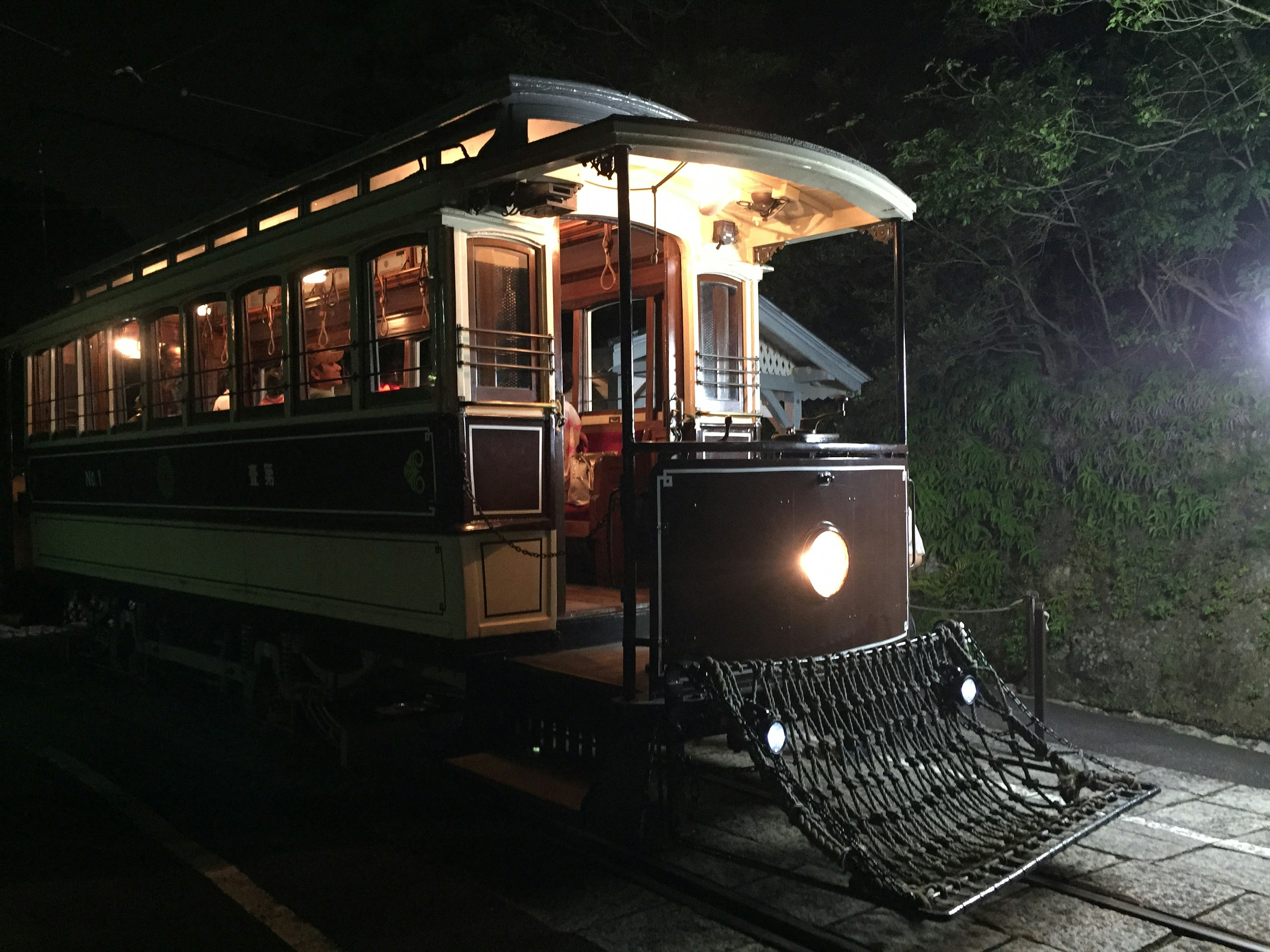 Un tram vintage illuminato di notte con esterno in legno e finestre luminose