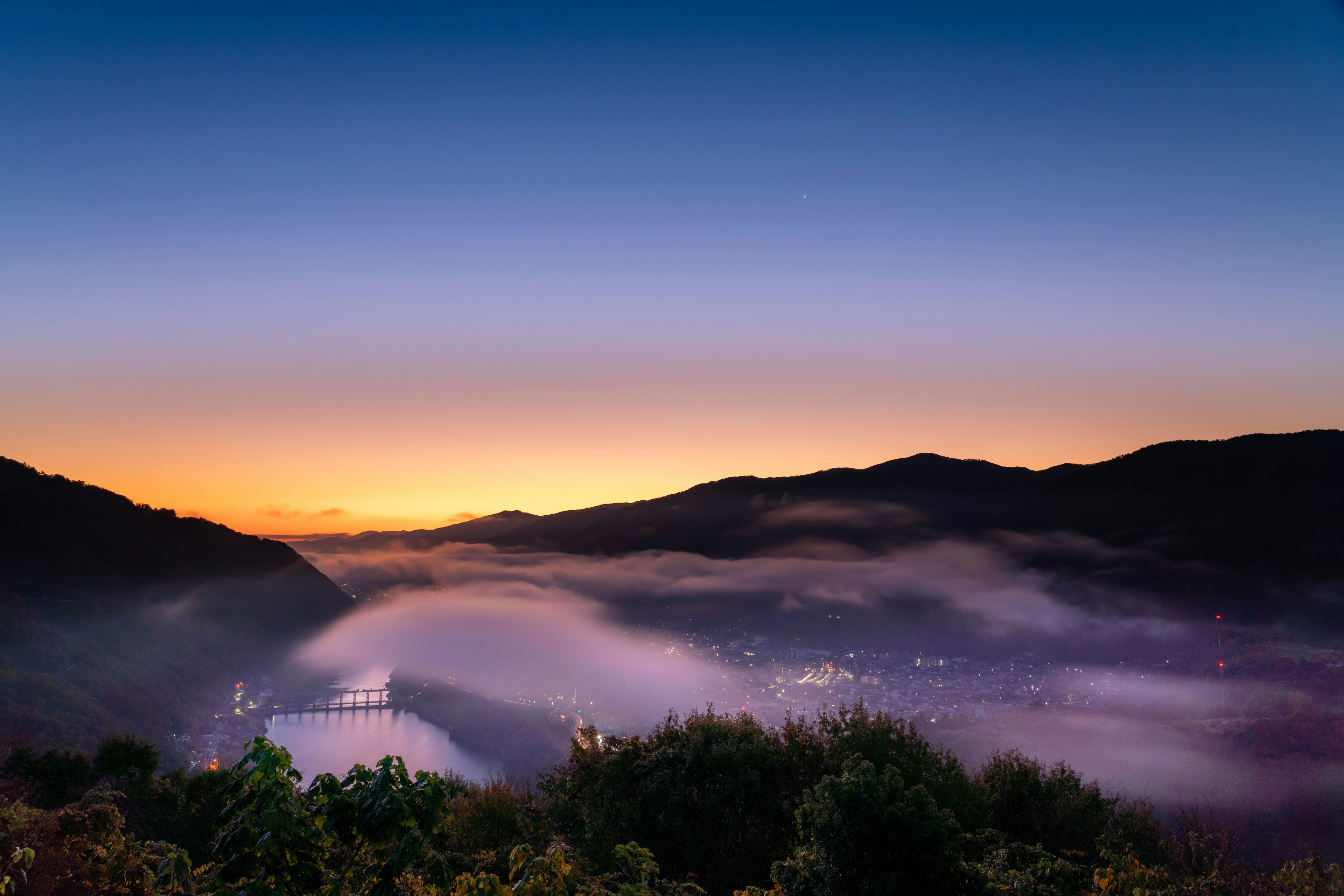 Bellissimo paesaggio al tramonto su una città circondata da montagne e nebbia