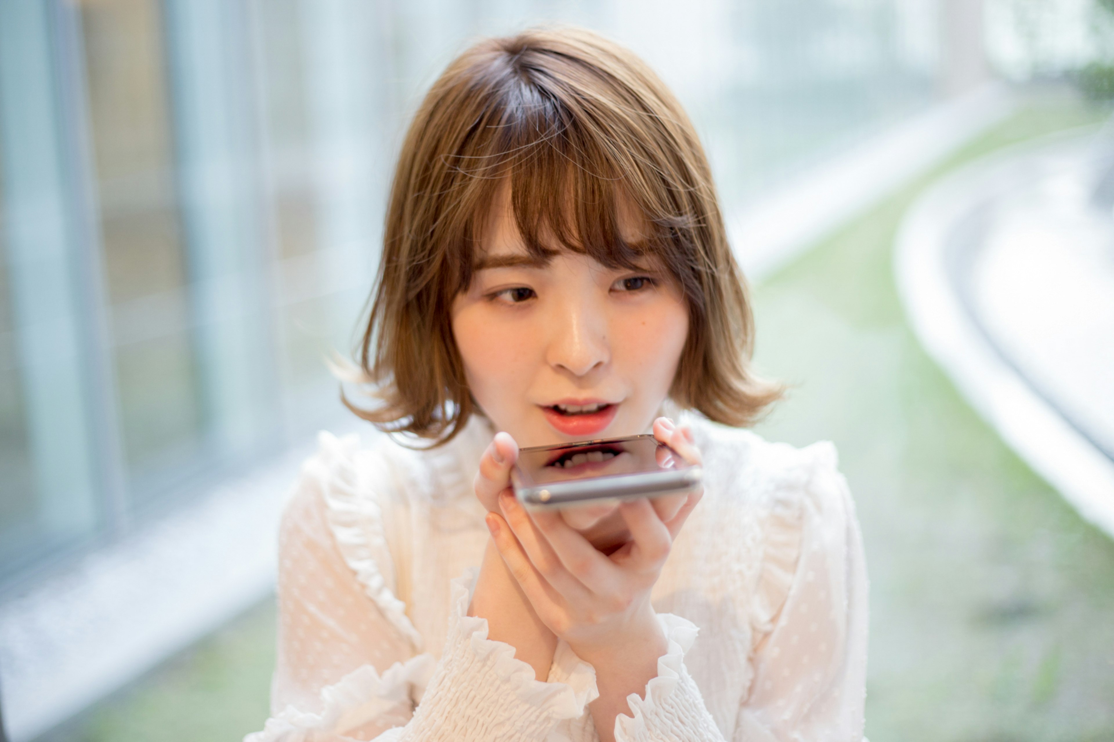 A woman using a smartphone while wearing a white blouse