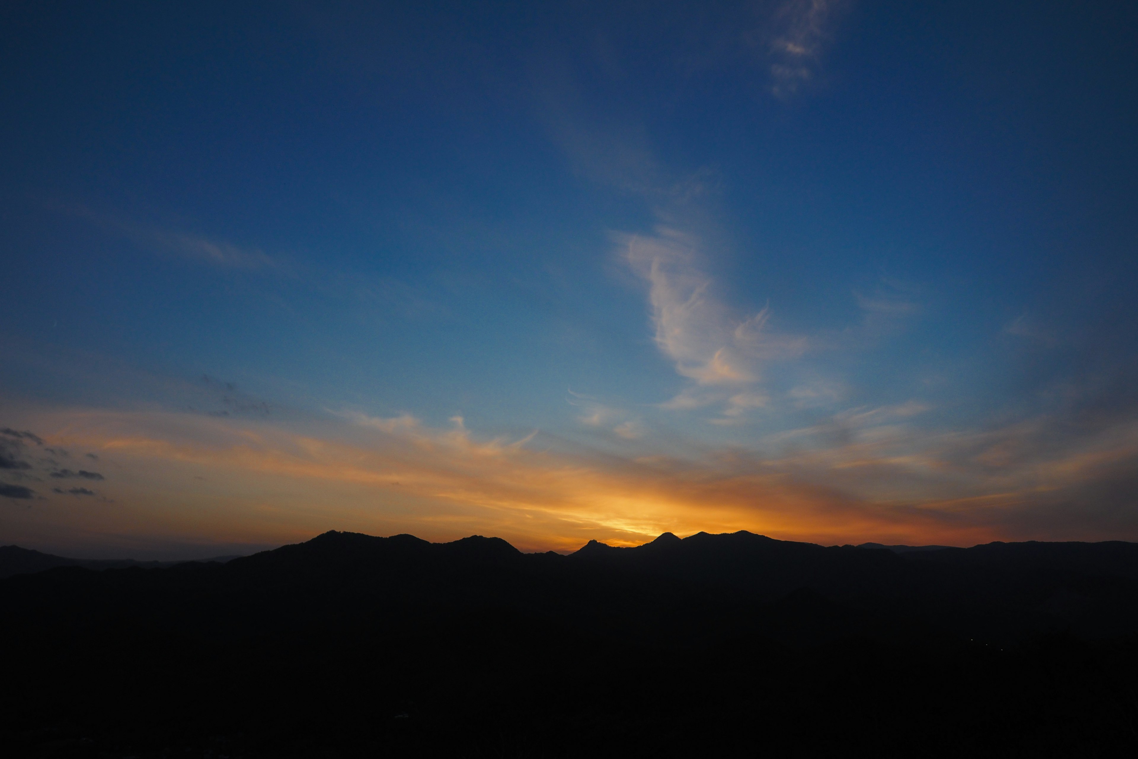 Silhouette von Bergen vor einem blauen Himmel mit einem lebhaften Sonnenuntergang