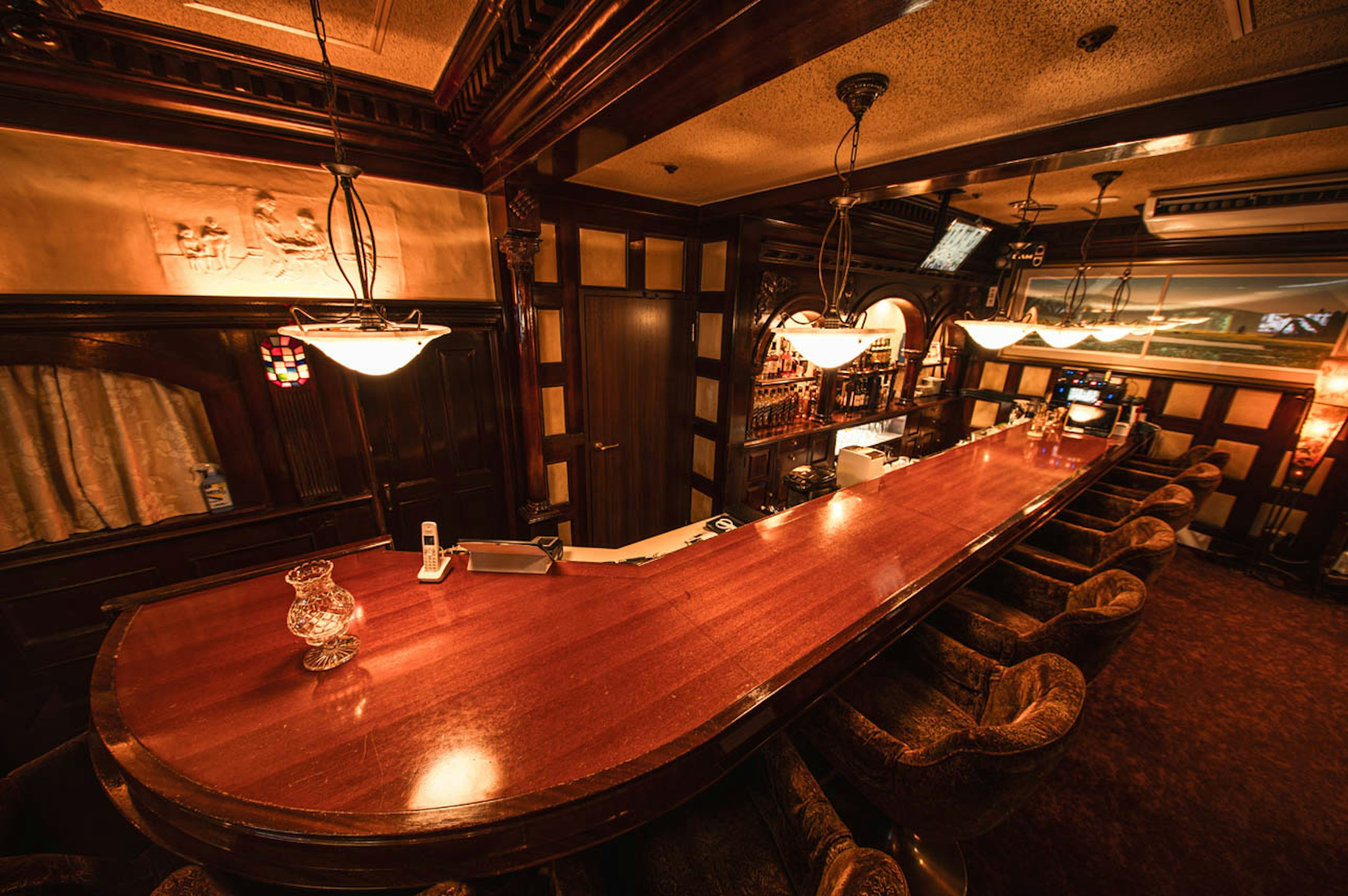 Cozy bar interior featuring a long wooden counter and warm lighting