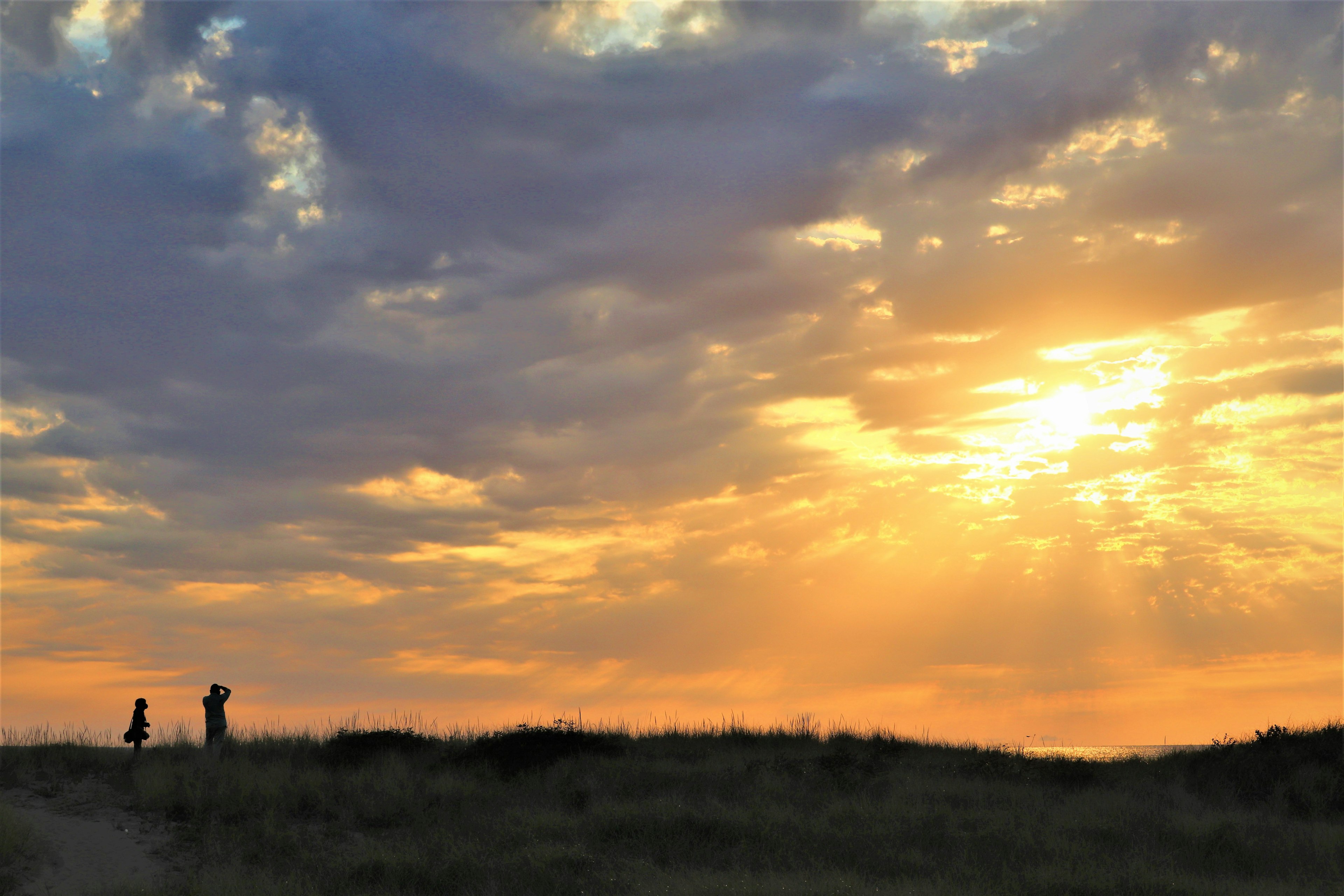 Silhouette of two people against a sunset sky