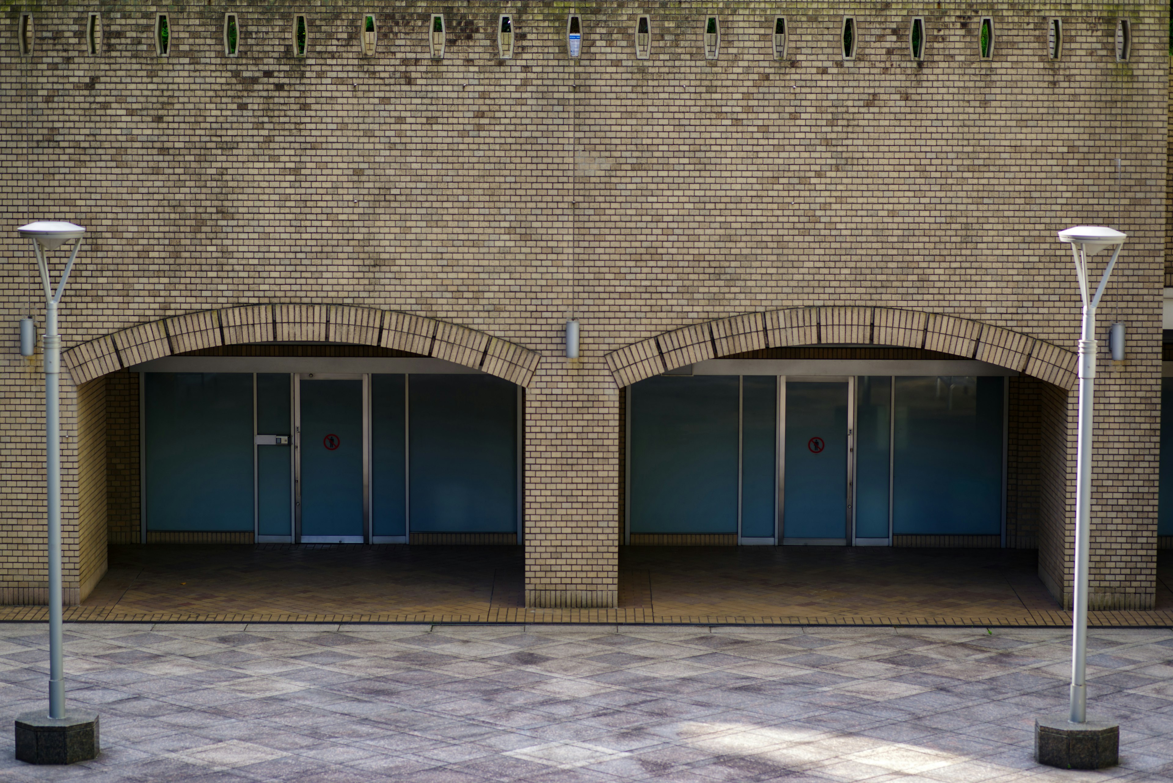 Un bâtiment en pierre avec deux fenêtres en arc et des lampadaires modernes