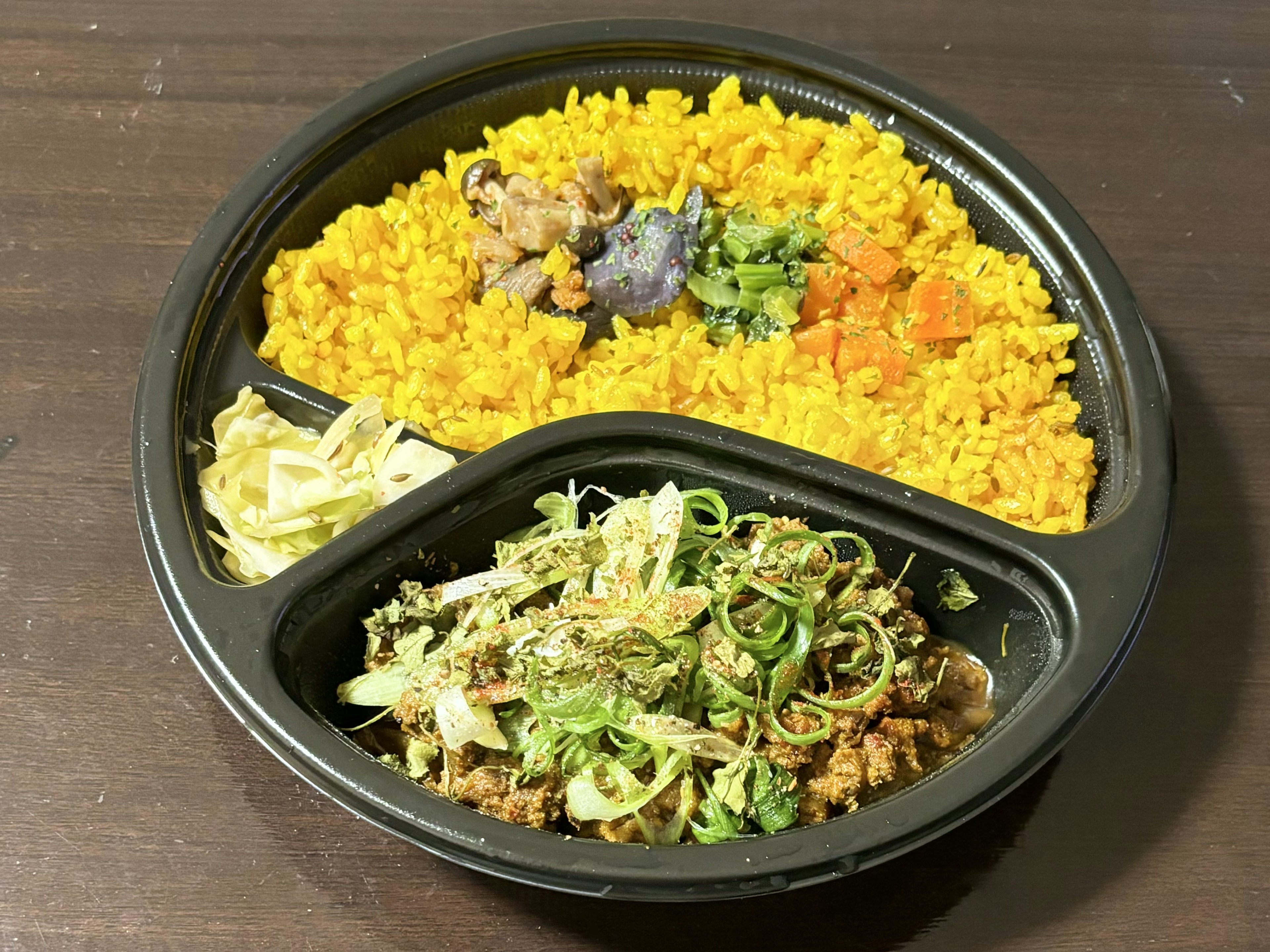 Colorful bento box featuring yellow rice and meat dish