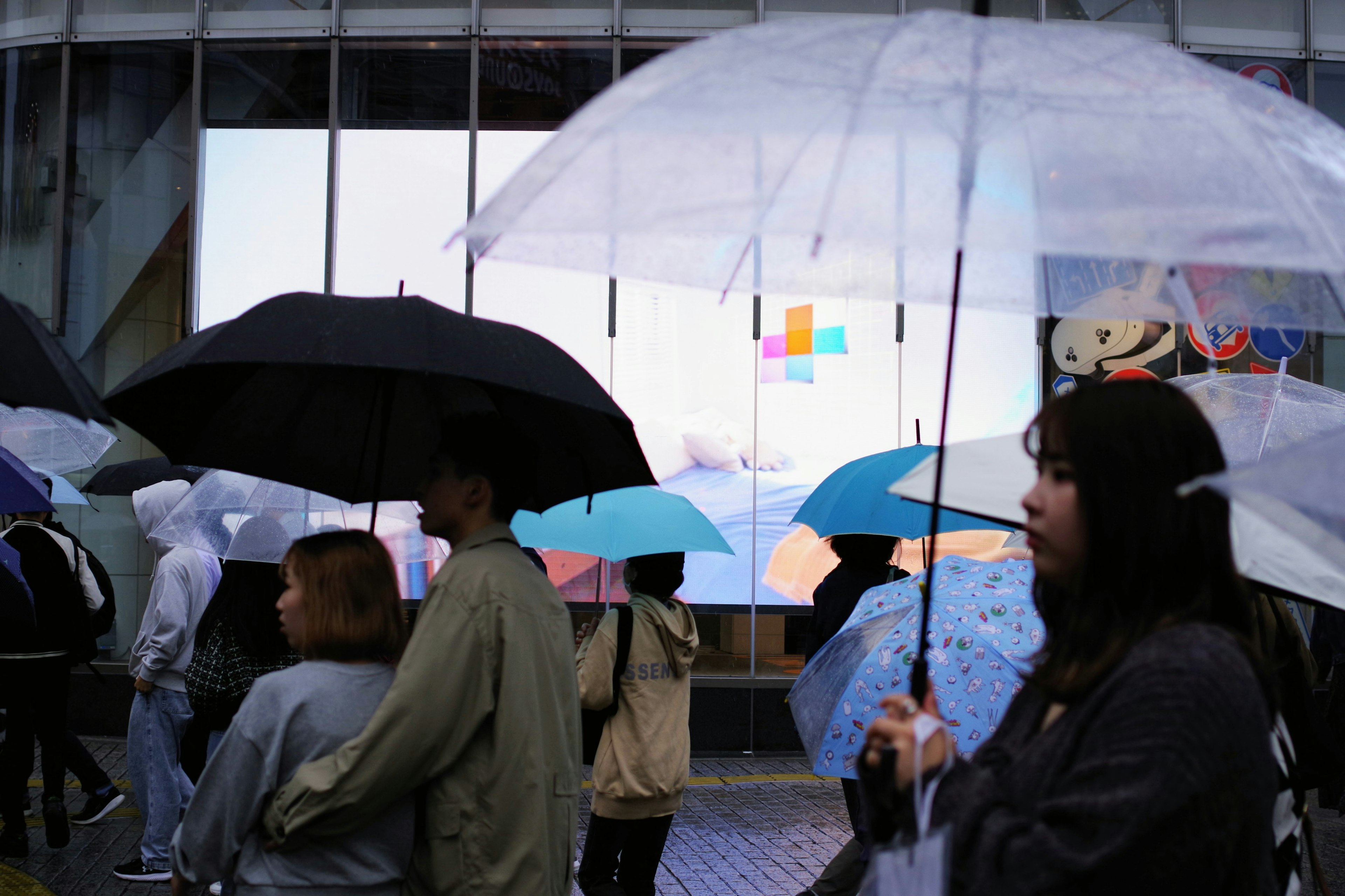 Des personnes tenant des parapluies sous la pluie avec un mélange de parapluies colorés et noirs