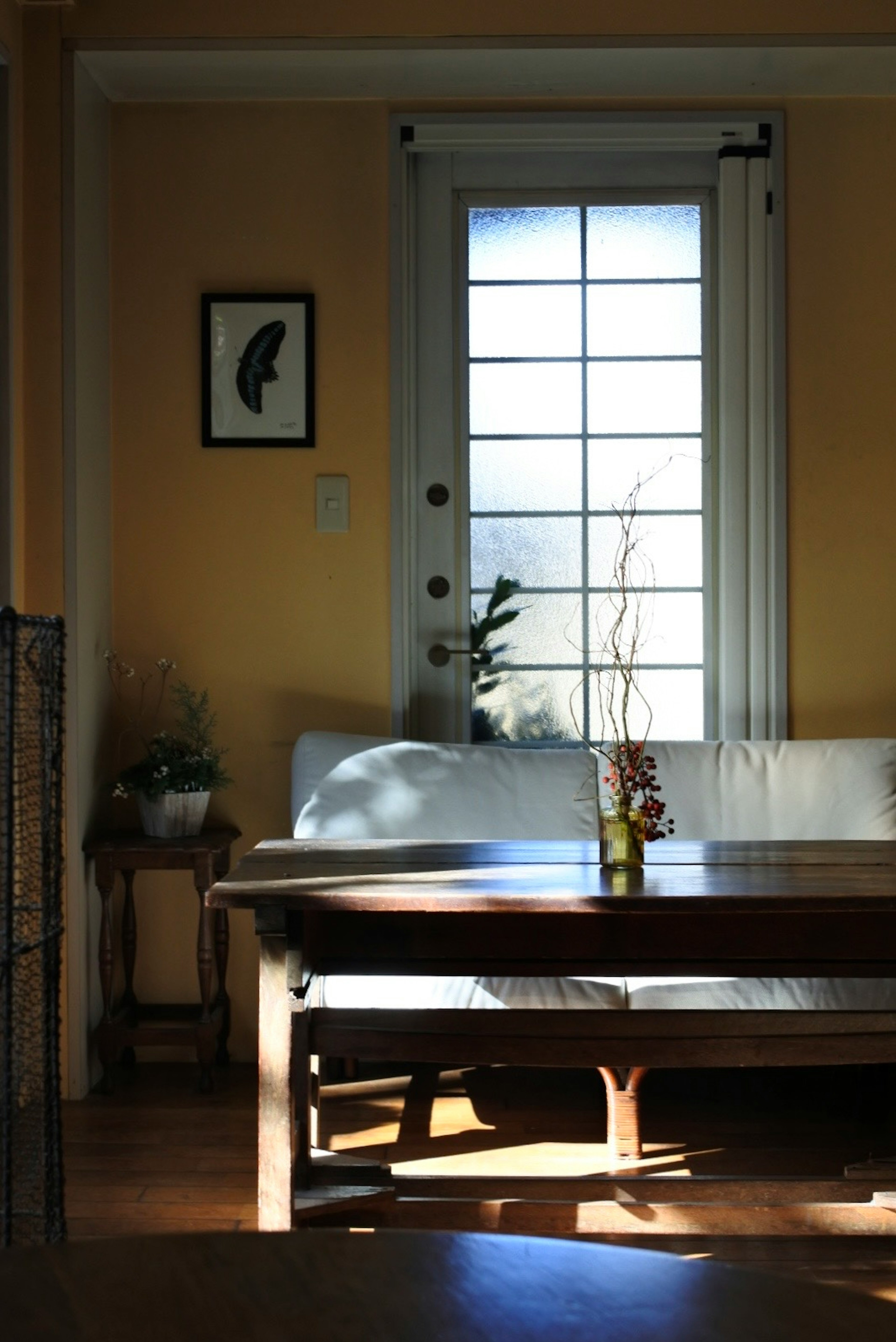 Chambre confortable avec des murs jaunes, un canapé blanc et une table en bois