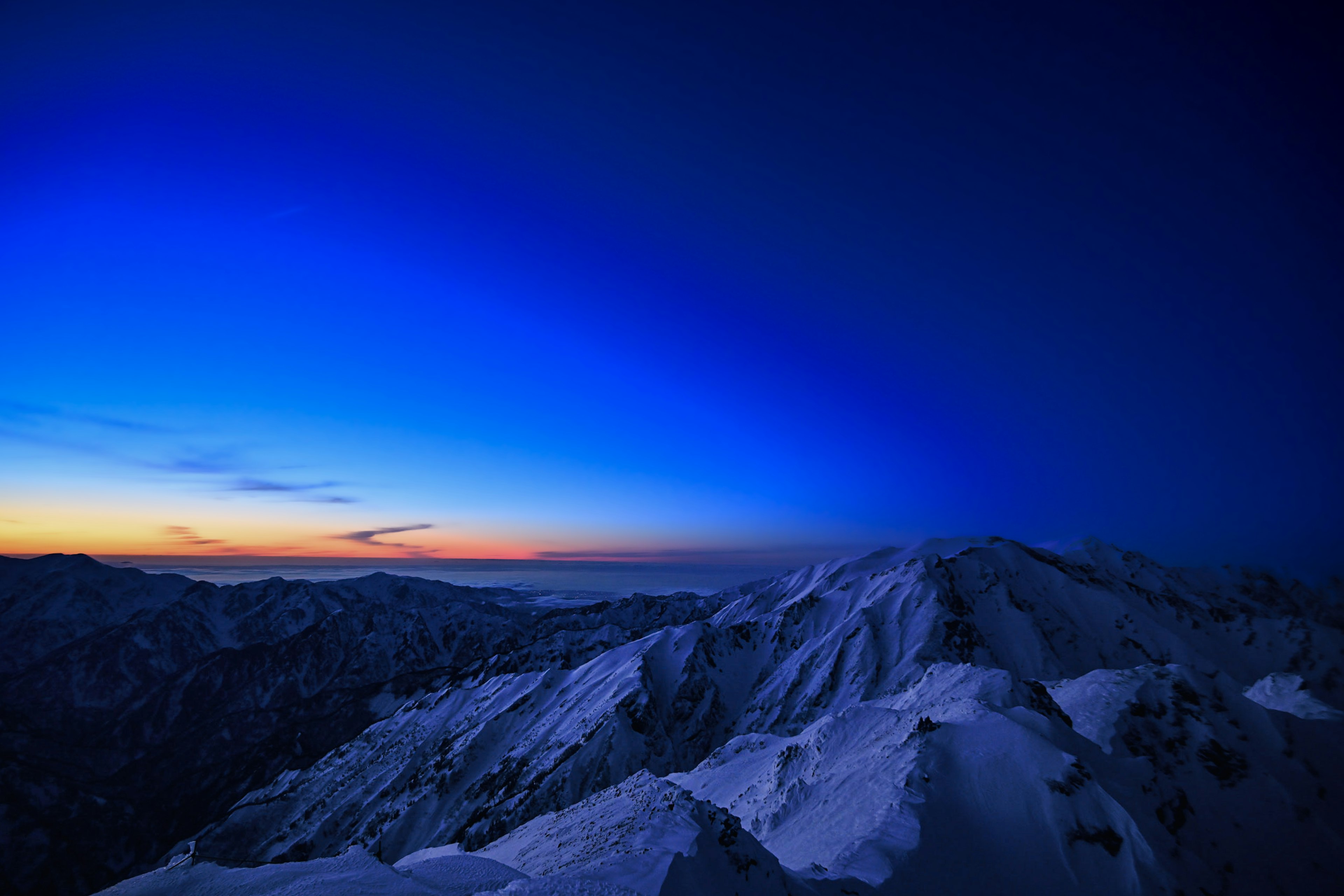 Snow-covered mountain peaks under a gradient blue sky